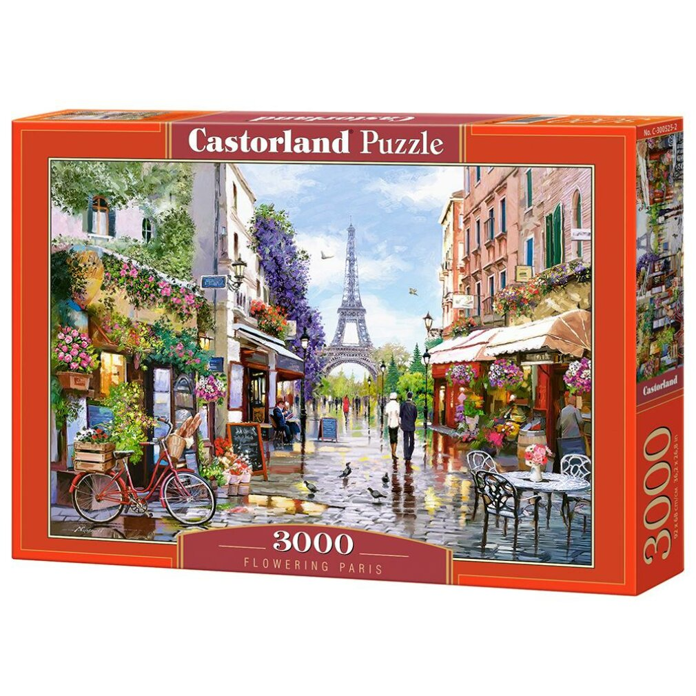 Eine Puzzleschachtel zeigt eine Pariser Straßenszene mit dem Eiffelturm. Menschen gehen auf einer nassen Straße, umgeben von Gebäuden und Blumen.