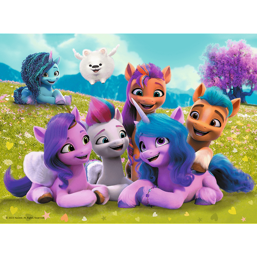 Een groep kleurrijke tekenfilmpony's en een wit, harig personage op een grasveld met een boom en bergen op de achtergrond.
