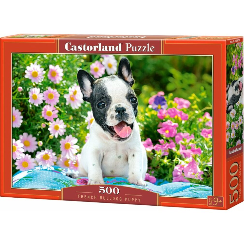 Ein Französisch-Bulldoggen-Welpe sitzt auf einem Kissen inmitten von Blumen, die Zunge heraus. Das Bild befindet sich auf einer Puzzle-Box.