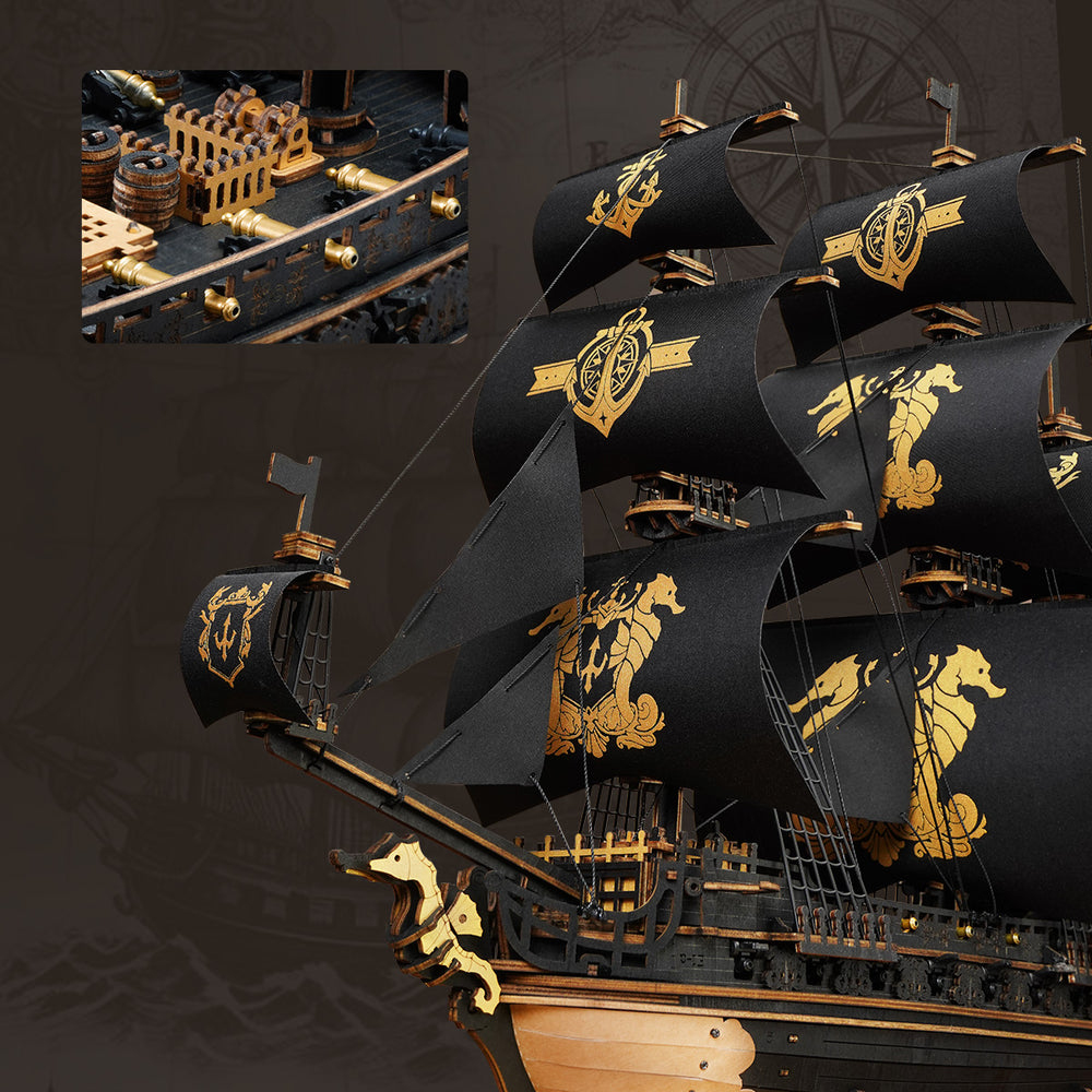 Un modèle de navire pirate en bois détaillé avec des voiles noires ornées de motifs dorés de hippocampes et d'emblèmes.