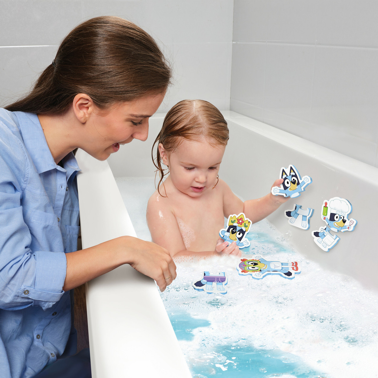 Eine Frau und ein Kind befinden sich in einer Badewanne mit Blasen. Zeichentrickfiguren sind im Wasser. Die Frau lächelt das Kind an.