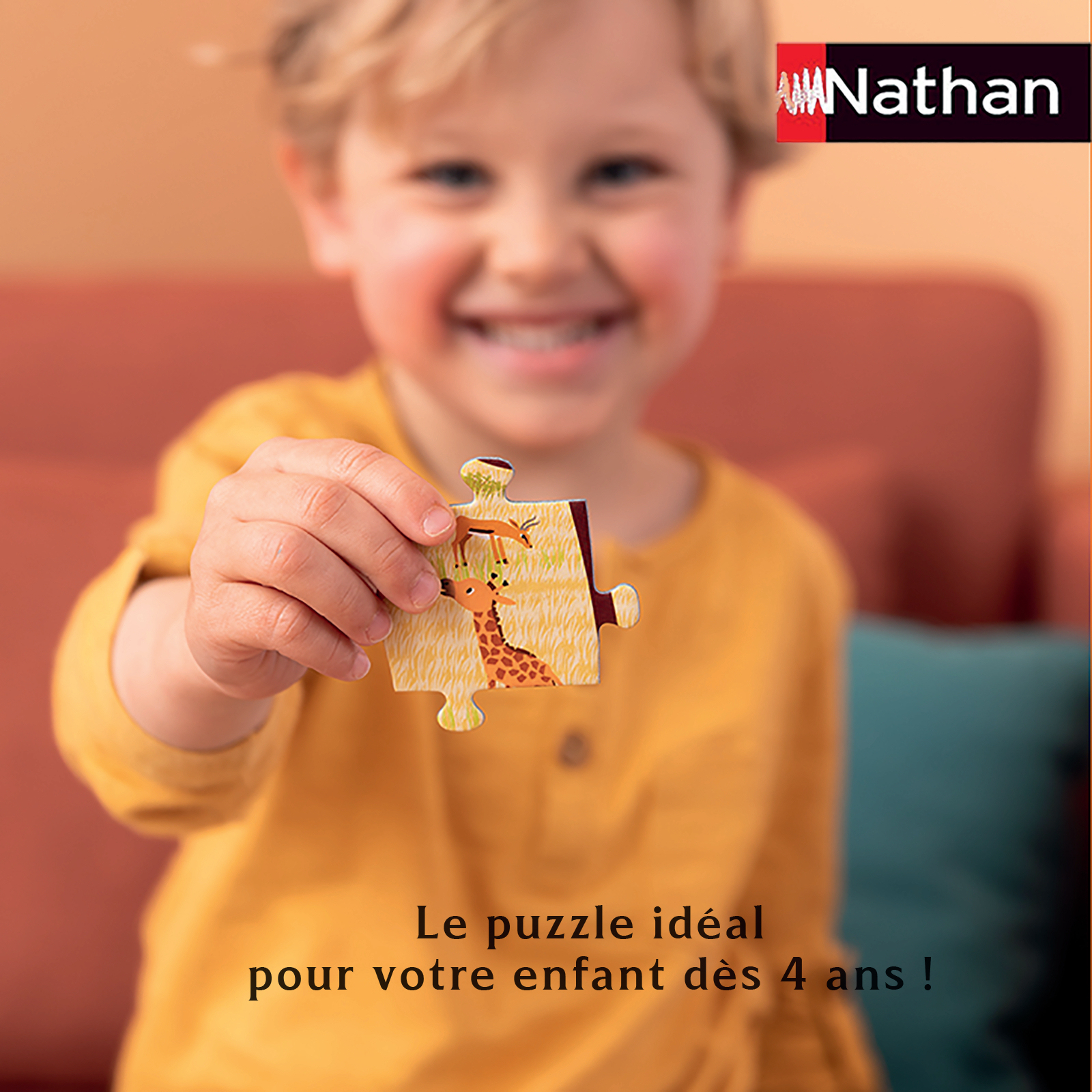 Ein lächelndes Kind hält ein Puzzleteil mit einer Giraffe und einem Hirsch. Nathan-Logo oben rechts.