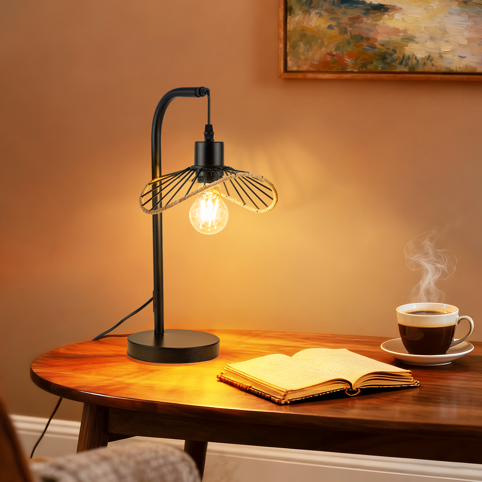 Lámpara encendida, libro abierto y taza de café sobre mesa madera. Pintura en la pared.