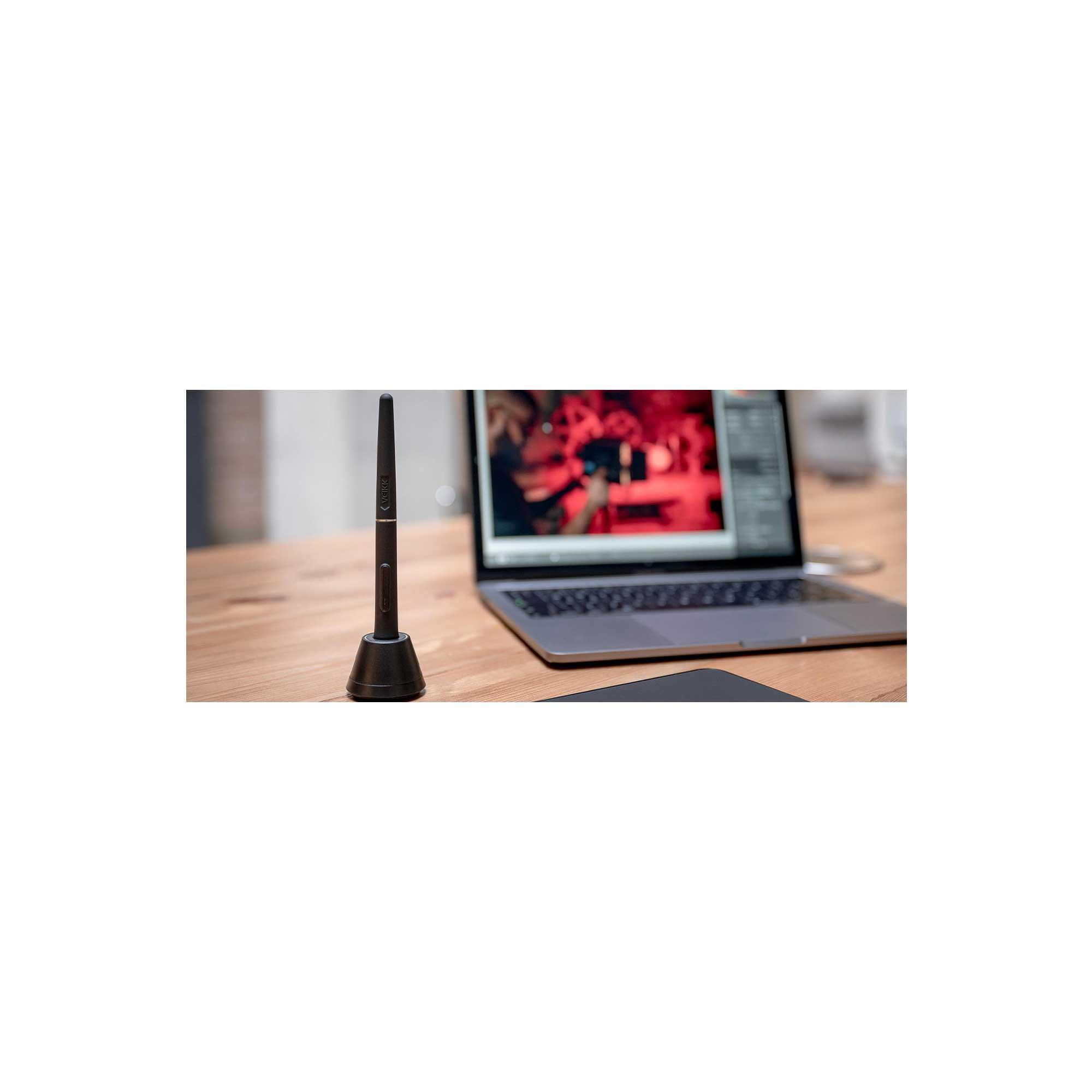 Bir stand üzerinde bir kalem, arayüz gösteren bir dizüstü bilgisayar ve ahşap bir masada bir tablet. Dizüstü bilgisayar ekranında bir kişi görünüyor.