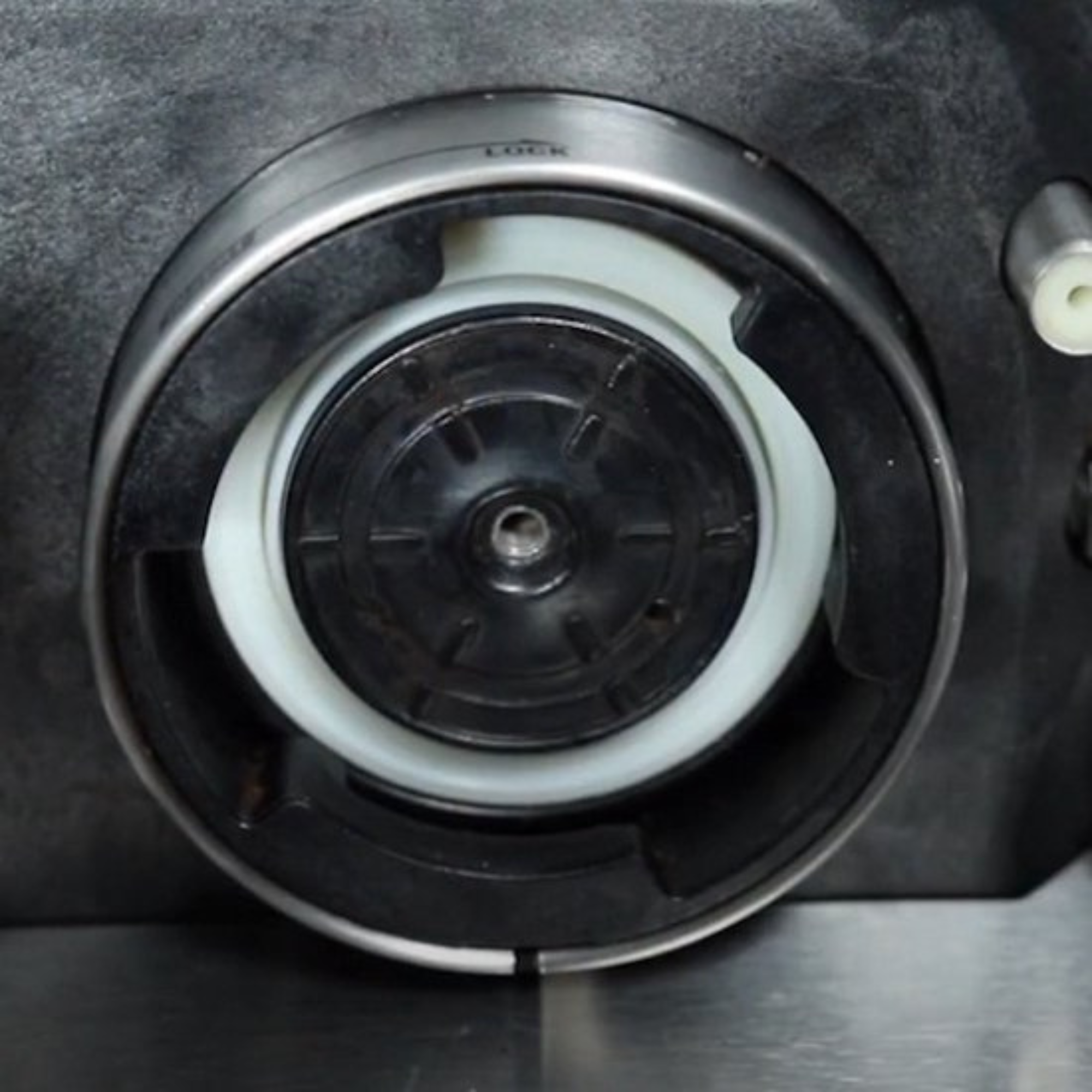 Close-up of a machine component. It has circular design with black, silver, and white elements.