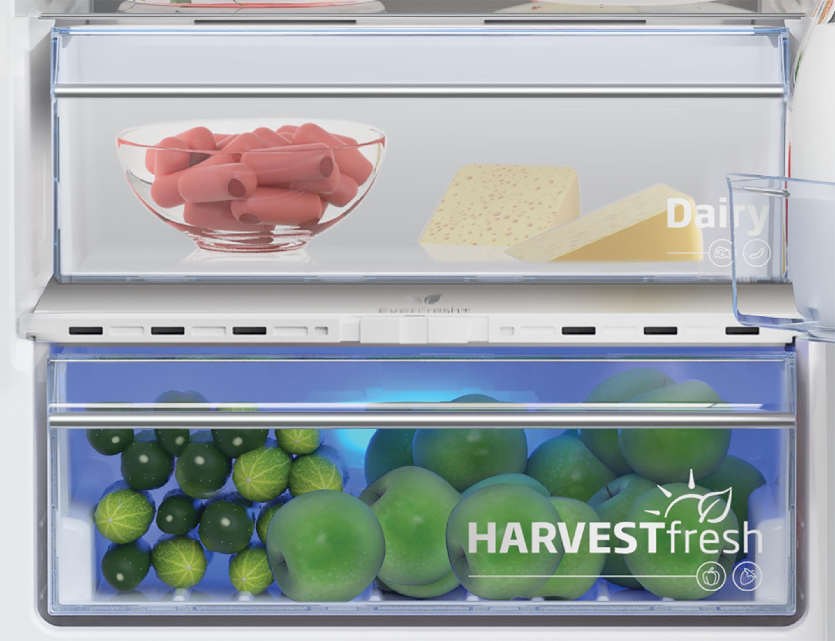 Wnętrze lodówki z jedzeniem. U góry: kiełbaski, ser. Na dole: jabłka, ogórki. Oznaczone 'HARVESTfresh'.