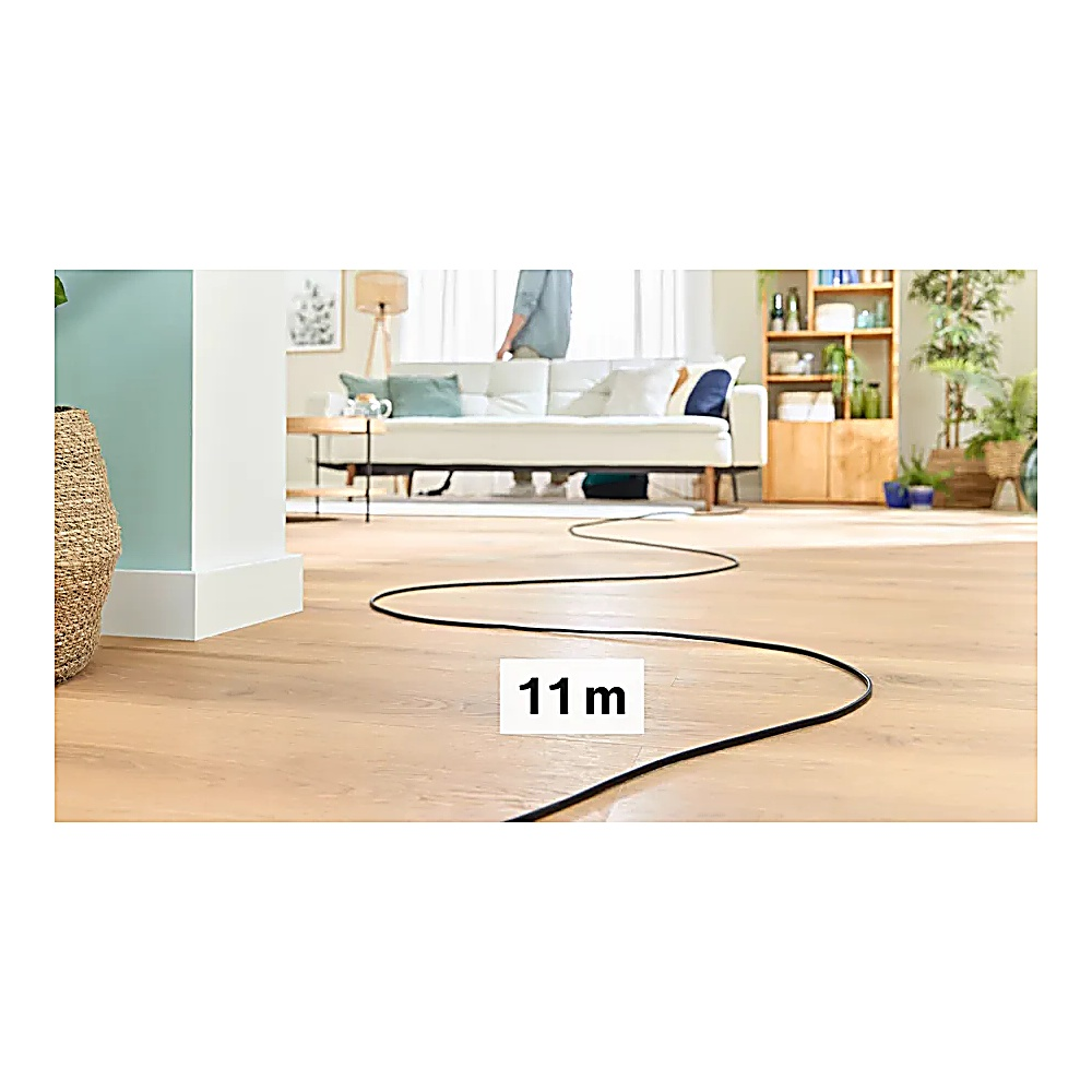 Czarny kabel rozciąga się po drewnianej podłodze. W tle widać białą sofę i osobę. Tekst '11 m' znajduje się na podłodze.