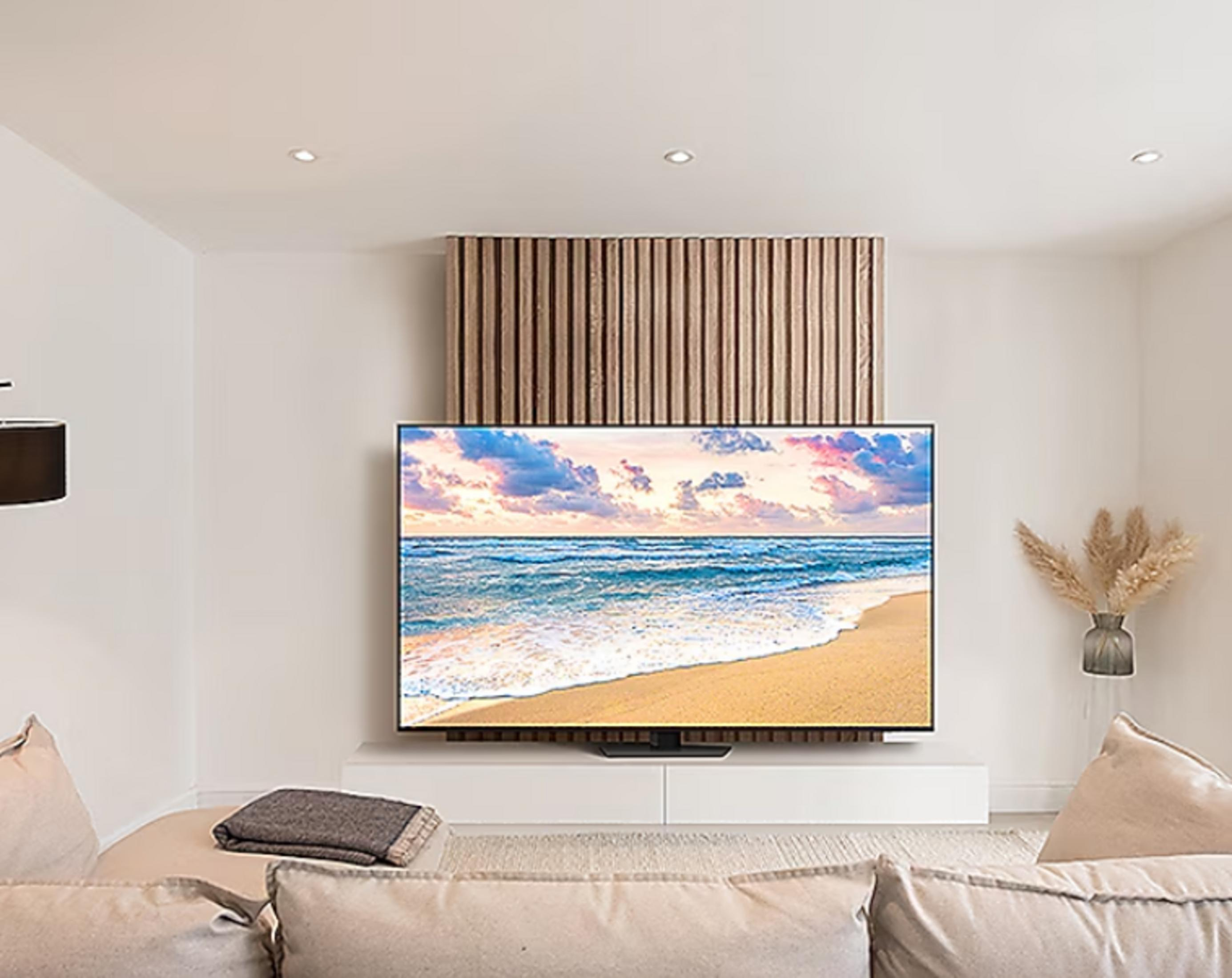 Salon z telewizorem z plażą, drewnianym panelem, beżową sofą i wazonem.