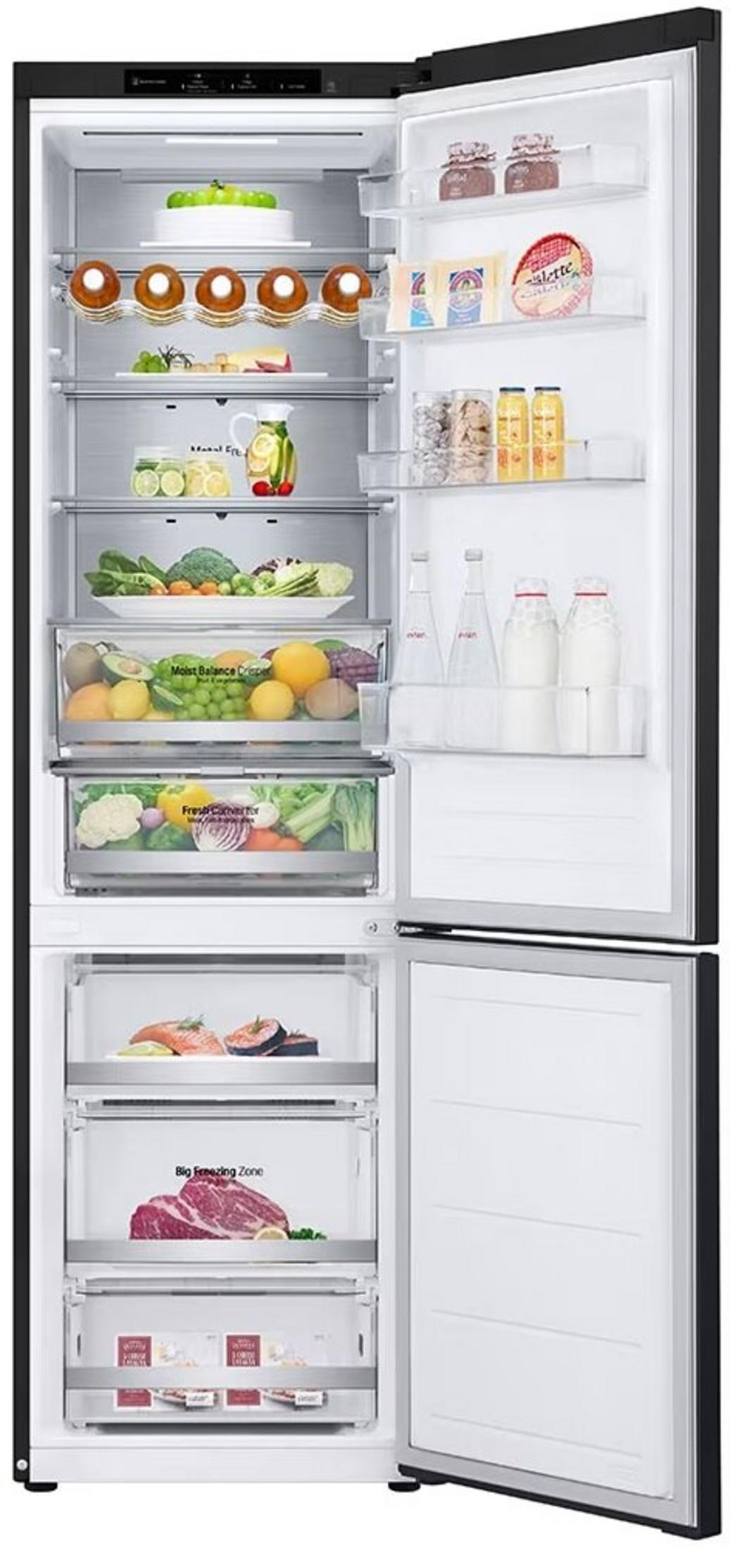 Otwarte drzwi lodówki, pokazujące żywność, taką jak owoce, warzywa, napoje i mięso na półkach i szufladach.