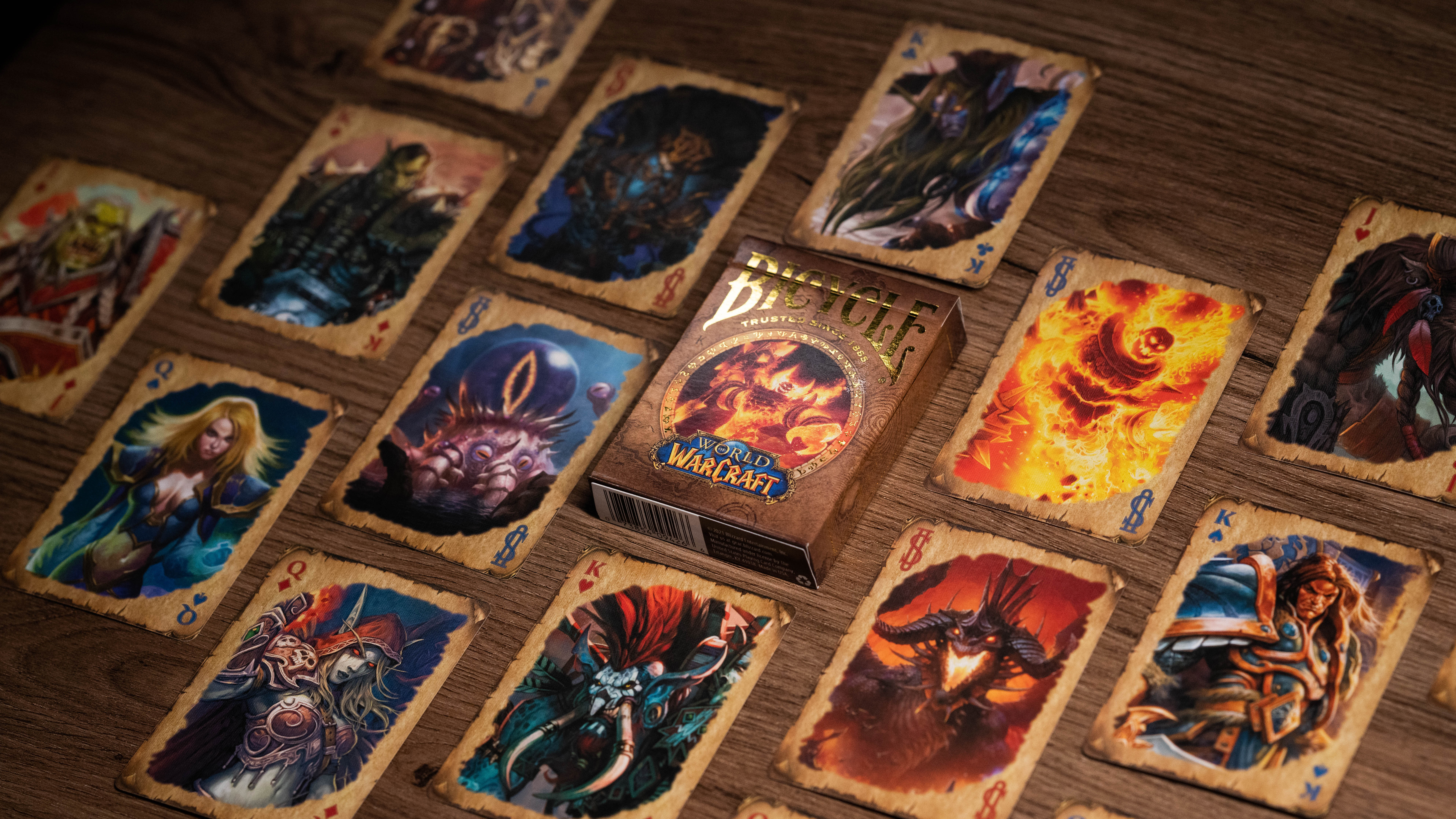 World of Warcraft Spielkarten auf Holzoberfläche. Ein Deck ist von Karten mit Charakteren und Kunst aus dem Spiel umgeben.