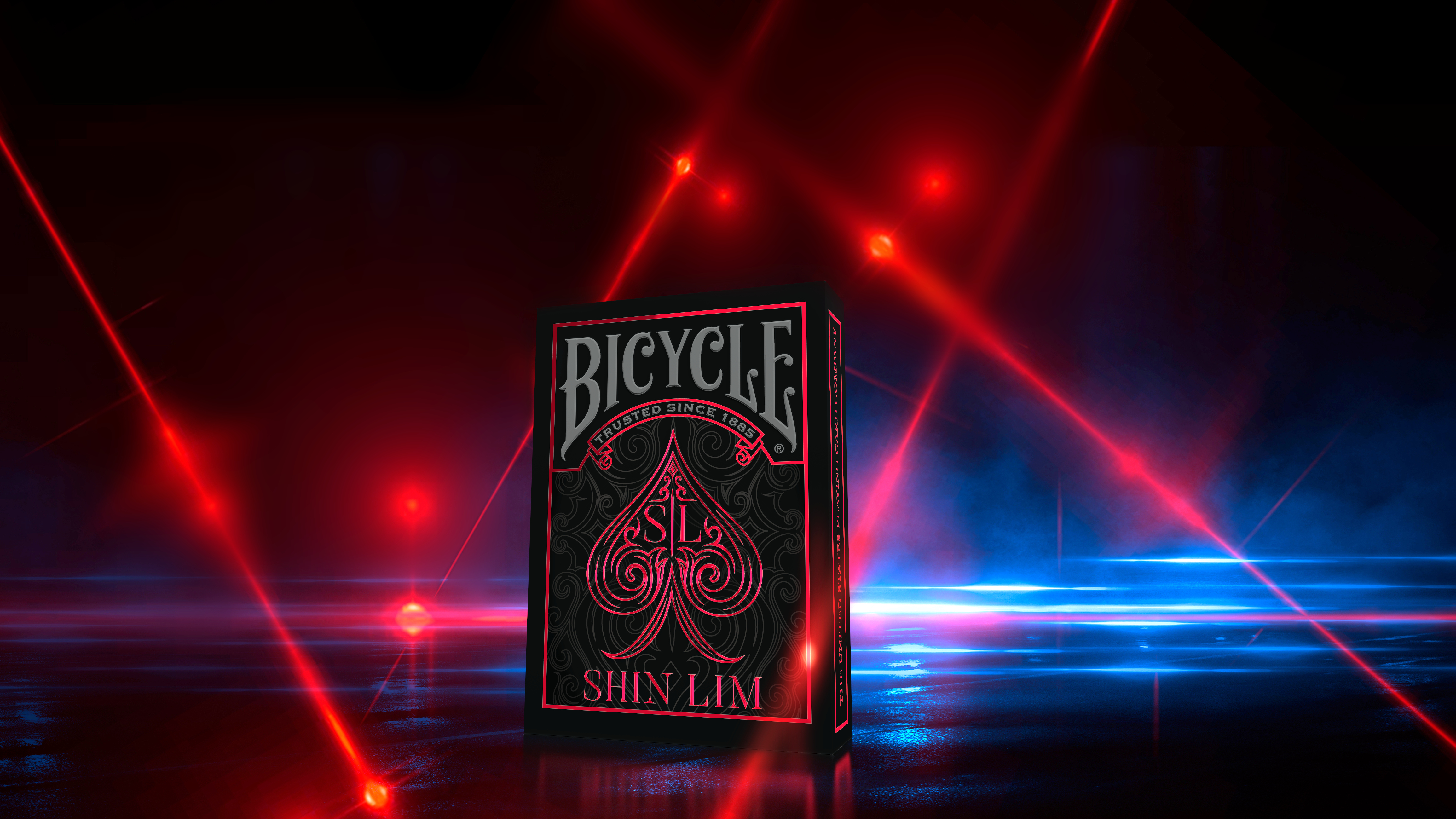 Ein Spielkartenspiel von Bicycle, Shin Lim Edition, wird von roten Strahlen vor einem dunklen, abstrakten Hintergrund beleuchtet.