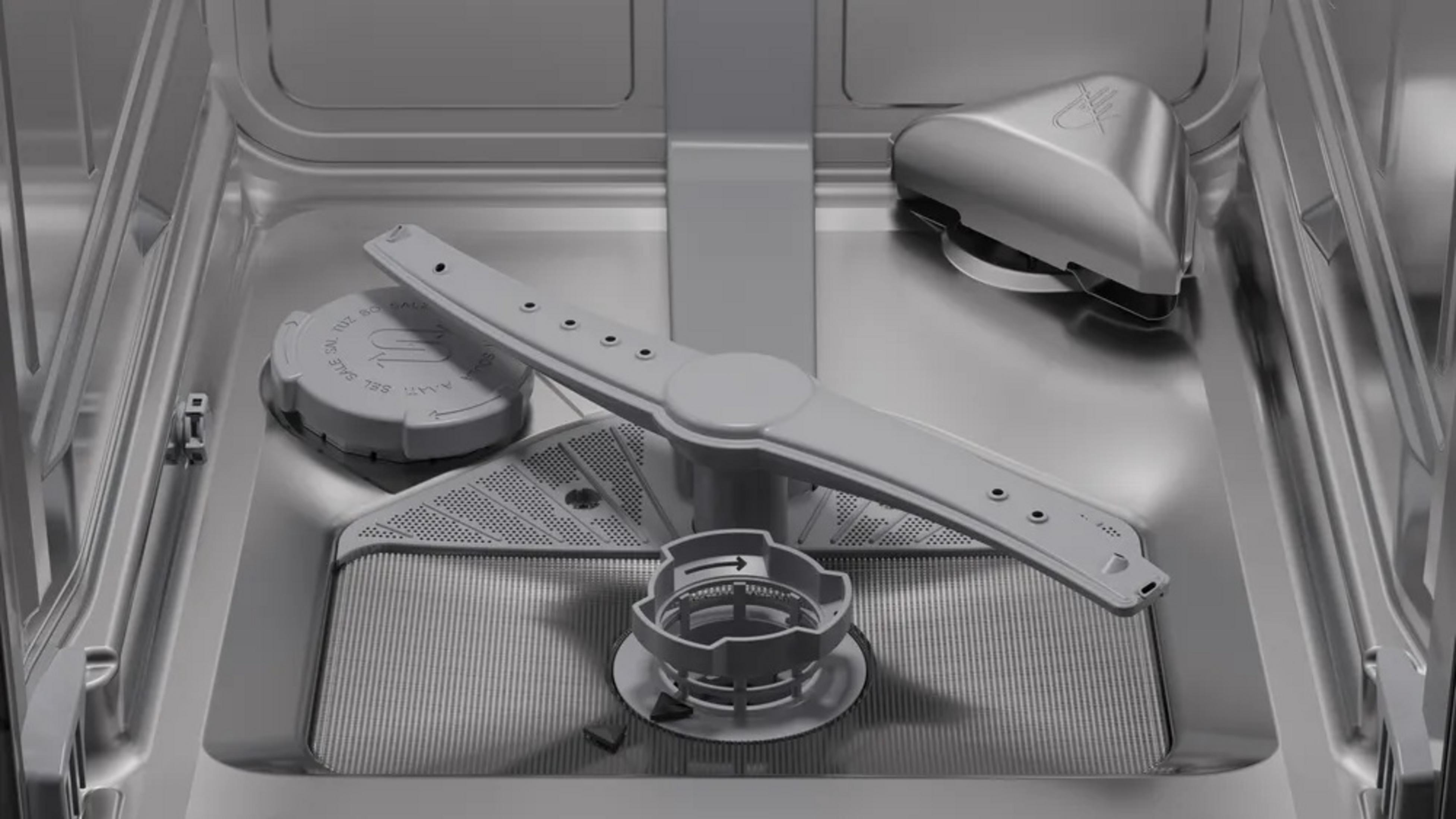 Wnętrze zmywarki z ramionami natryskowymi, filtrem i dozownikiem detergentu. Wszystkie części są szare.