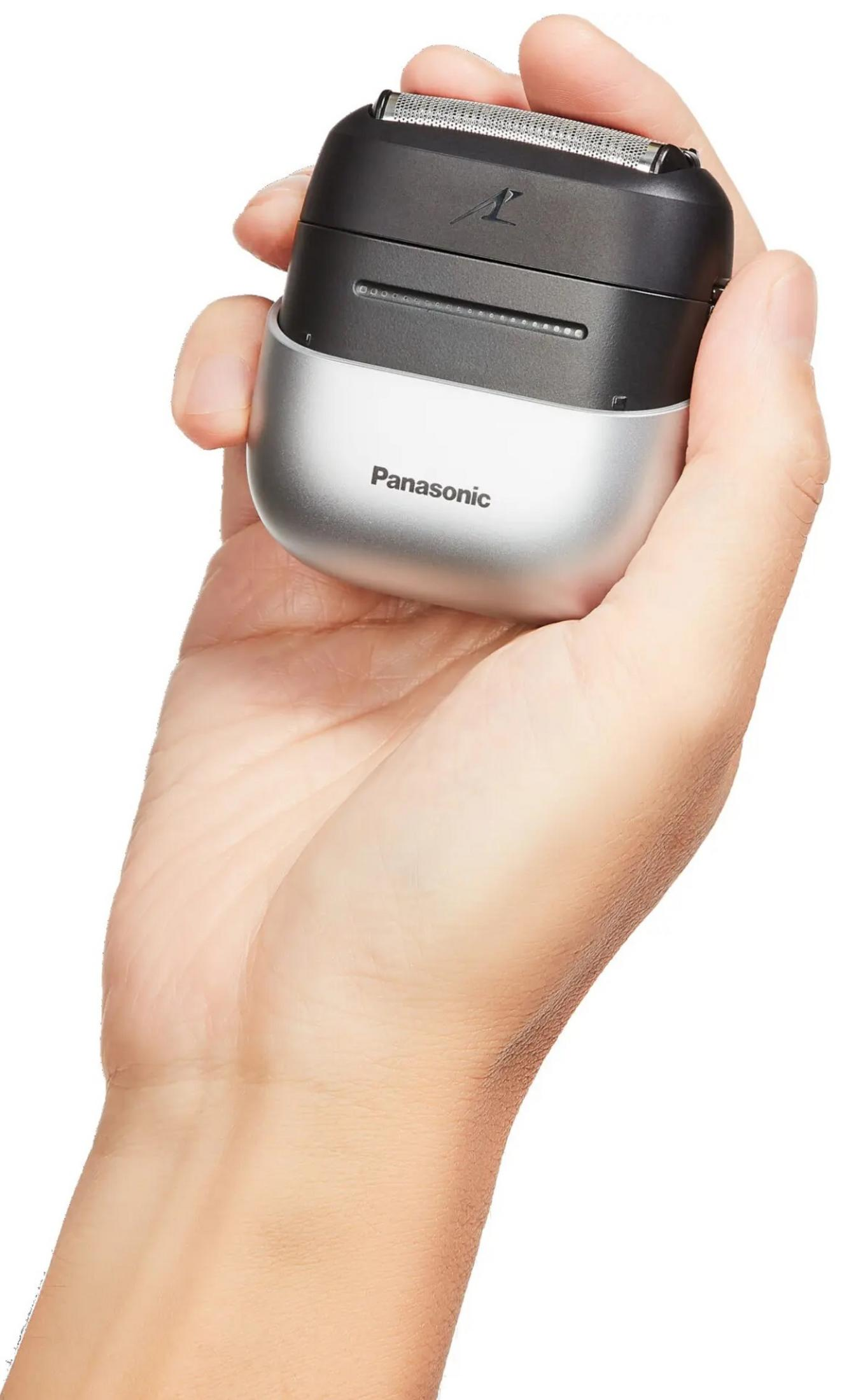 Eine Hand hält einen schwarzen und silbernen elektrischen Rasierer von Panasonic. Der Rasierer hat einen silbernen Sockel und einen schwarzen Deckel mit dem Markenlogo.
