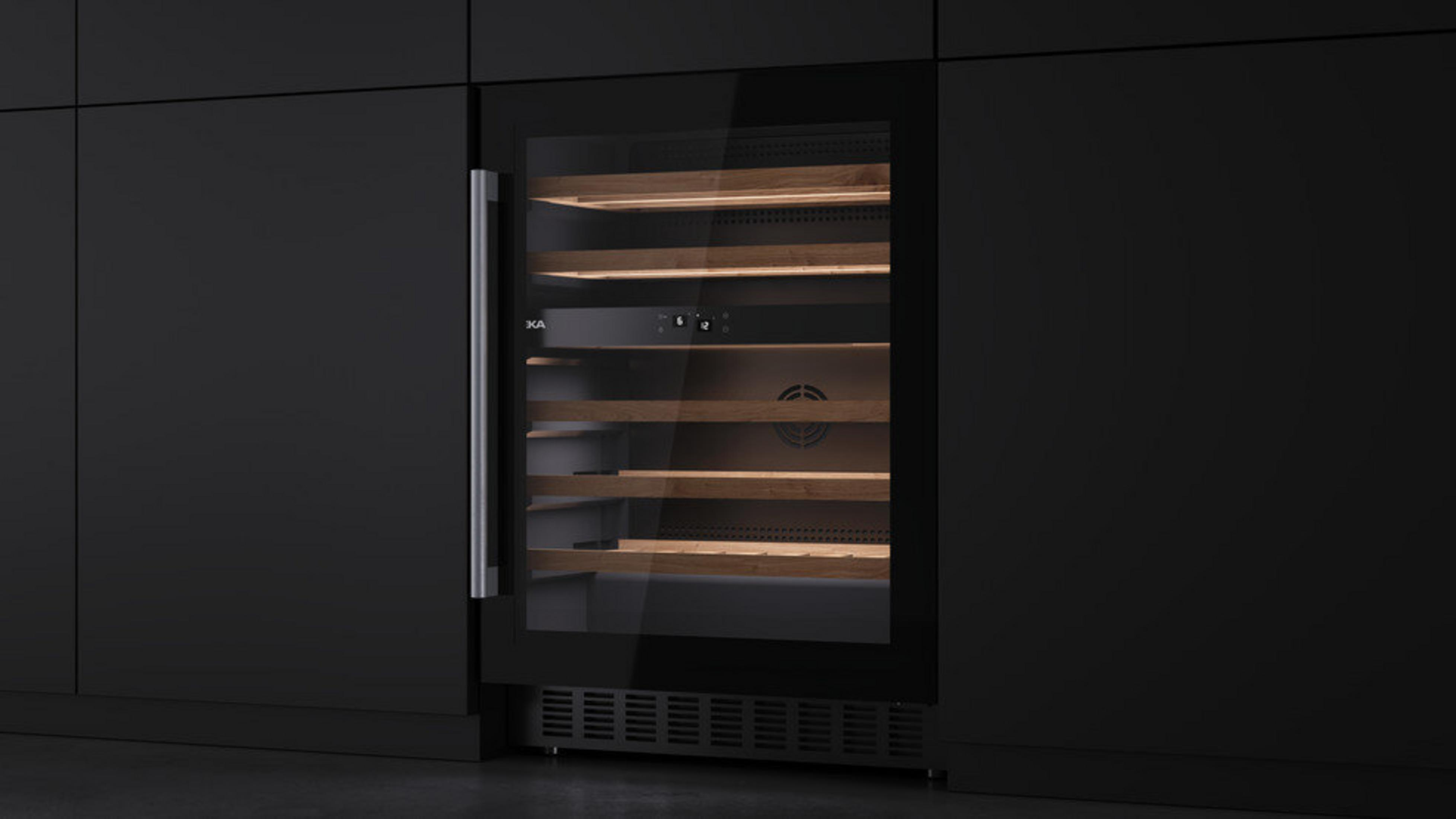 Nowoczesna chłodziarka do wina jest wbudowana w ciemną szafkę. Ma drewniane półki za szklanymi drzwiami i metalową rączkę.