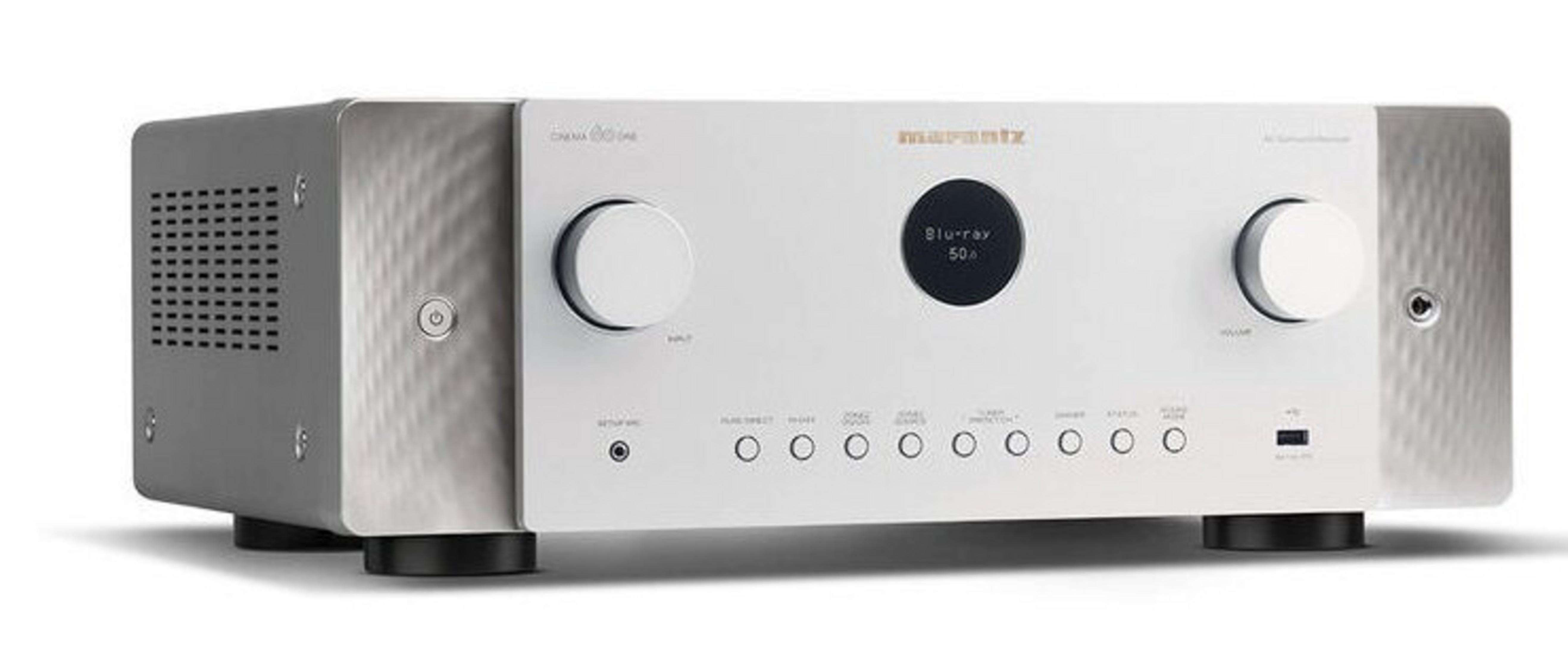 Srebrno-biały odbiornik Marantz. Posiada pokrętła, przyciski i centralny wyświetlacz z napisem 'Blu-ray 50a'. Stoi na czarnych nóżkach.