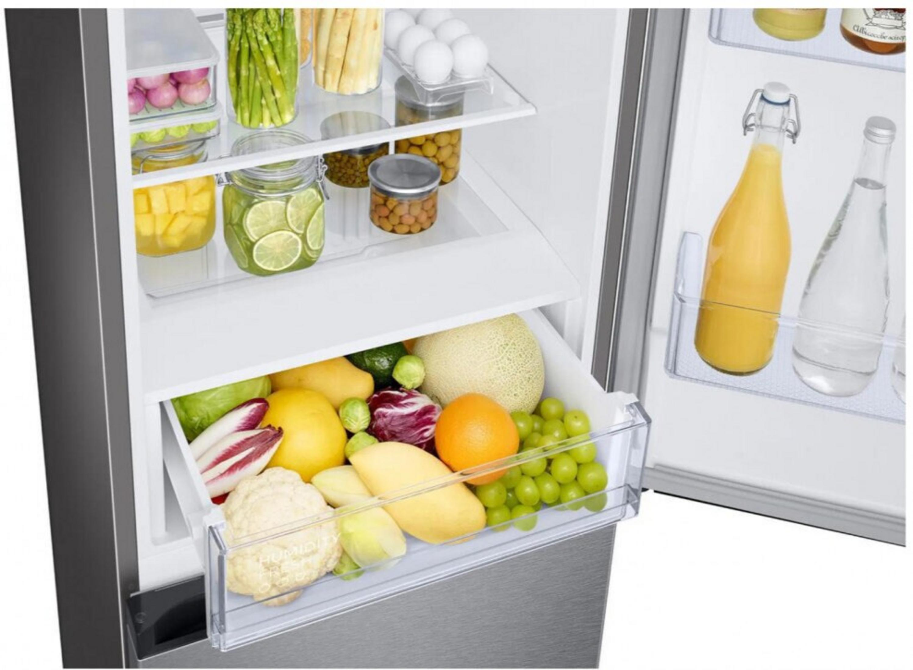 Frigorifero aperto pieno di frutta, verdura, uova e barattoli di cibo. Bottiglie di succo e acqua sullo sportello.