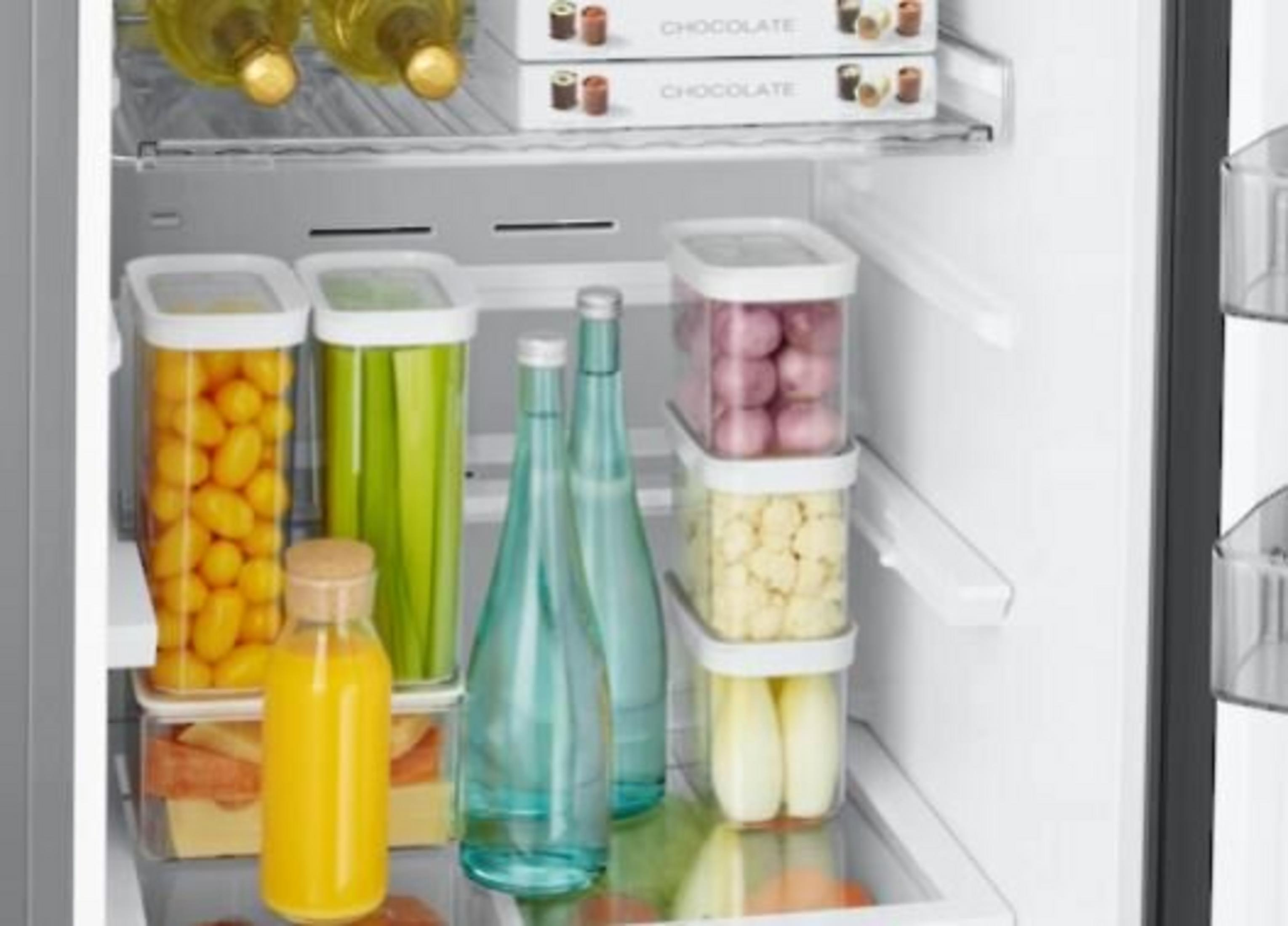 Koelkastinterieur met eten: sap, groenten, flessen en chocoladedozen.