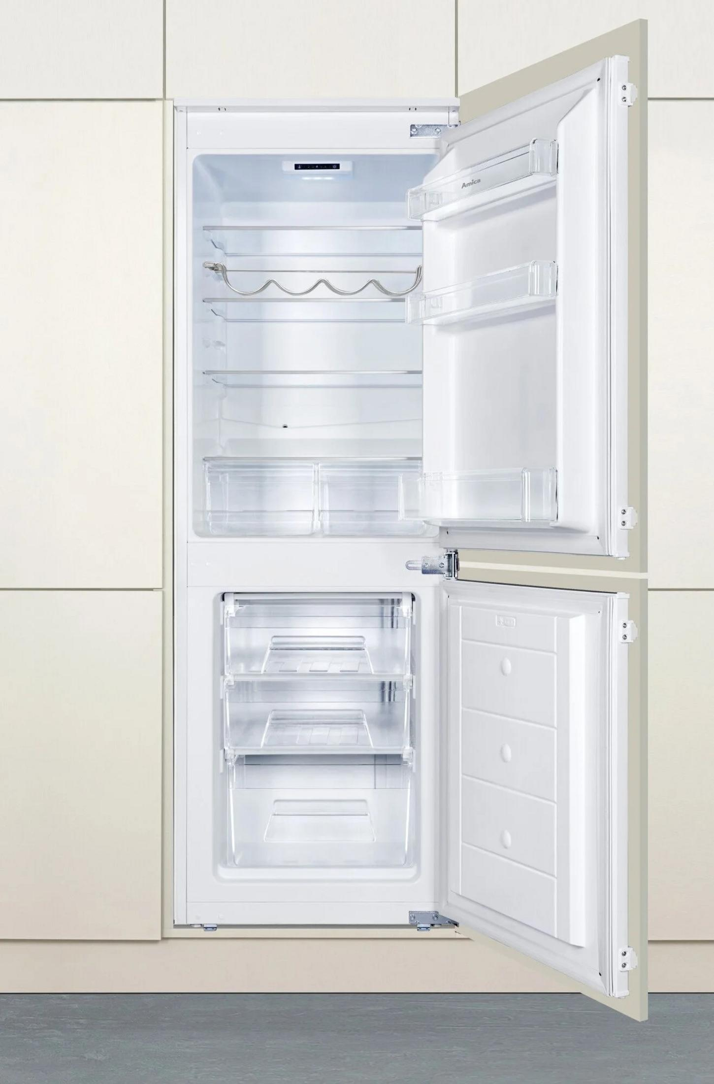 Frigorifero bianco aperto con ripiani e cassetti vuoti. La porta è aperta, rivelando l'interno. Armadi beige sullo sfondo.