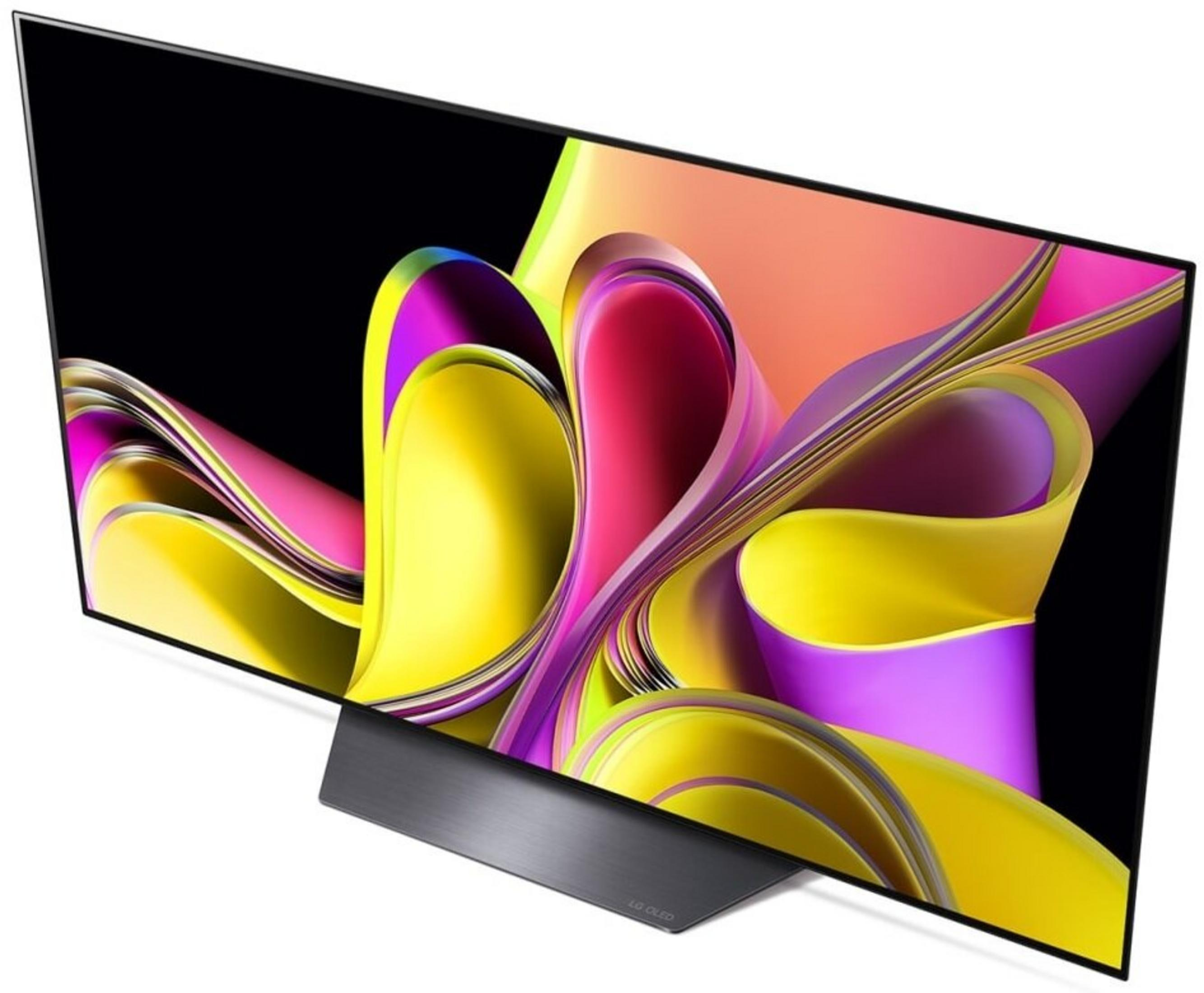 Un televisore LG OLED mostra un'arte astratta colorata. La TV è nera con un supporto argentato. L'arte è gialla, rosa e viola.