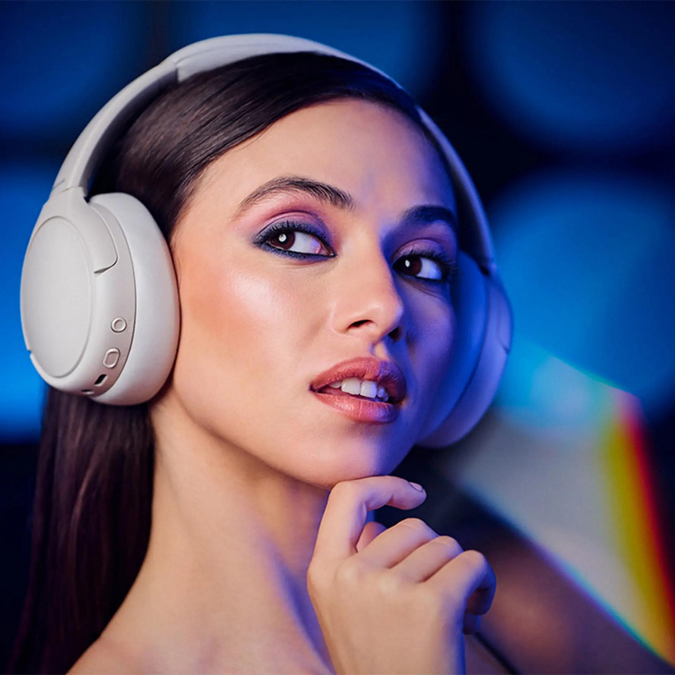 Une femme avec un casque regarde ailleurs. Elle se touche le menton avec un doigt. Le fond est bleu avec un arc-en-ciel.