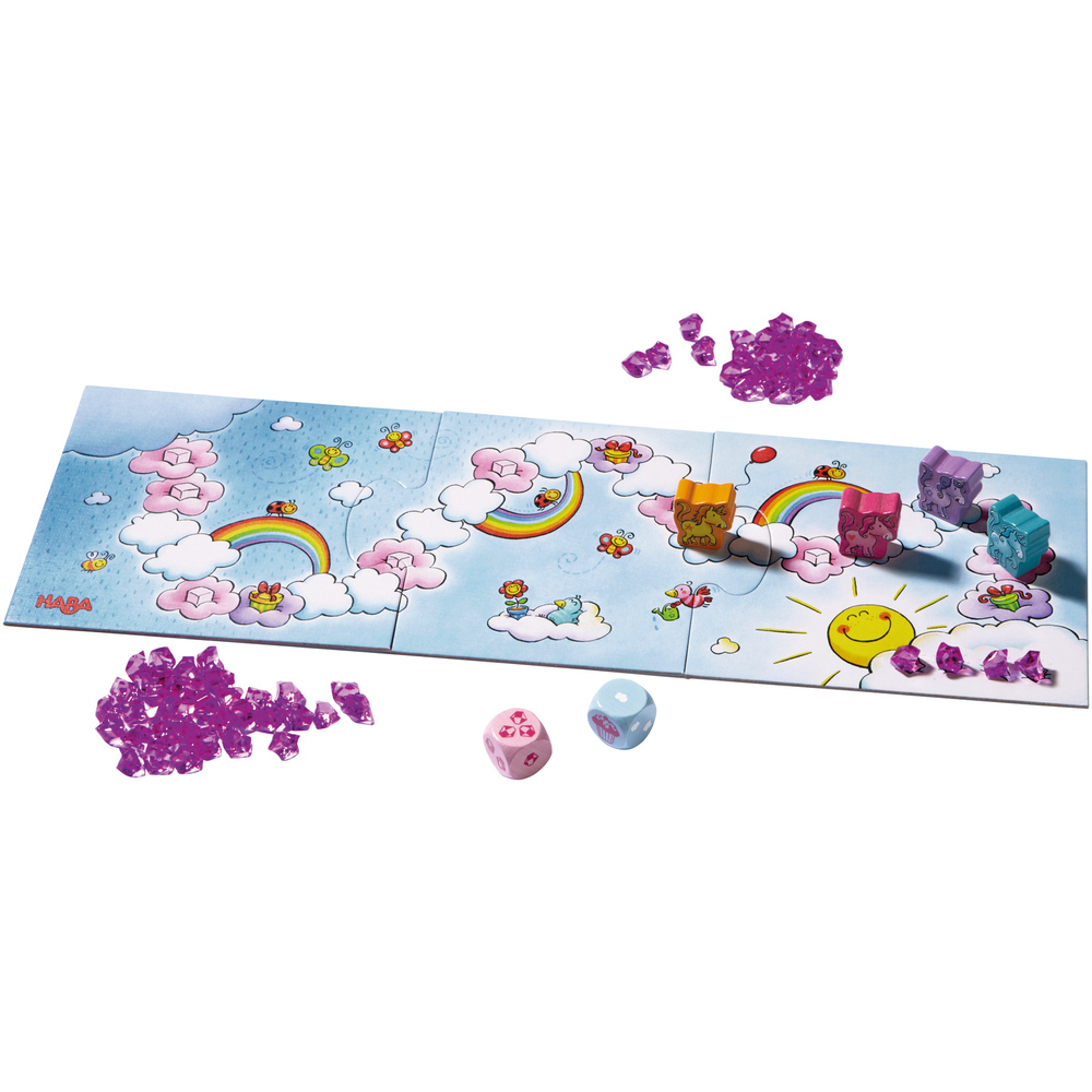 Brettspiel mit Regenbogen, Wolken, Würfeln und bunten Blöcken. Lila Edelsteine sind um das Brett verstreut.