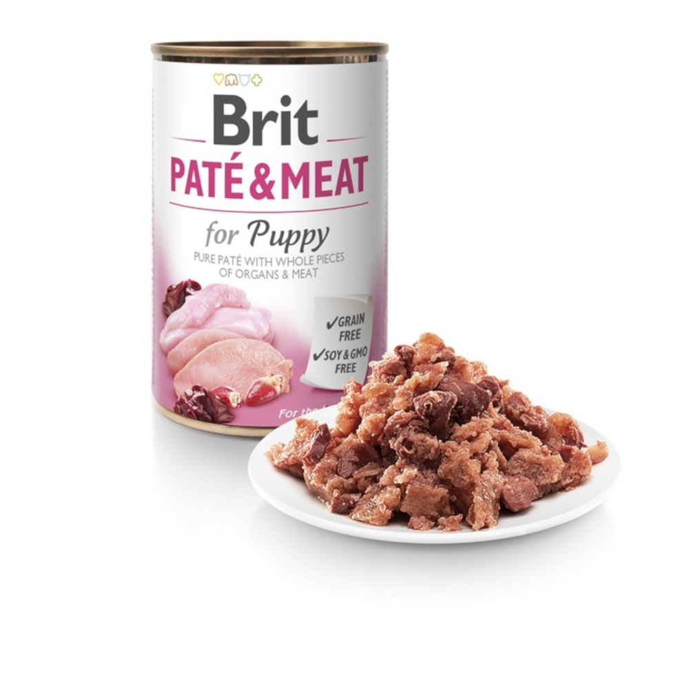 Puszka Brit Paté & Meat dla szczeniąt z górą jedzenia na białym talerzu. Puszka zawiera tekst i zdjęcia mięsa.