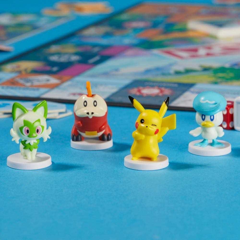 Cuatro figuras de Pokémon sobre una superficie azul. Pikachu guiña un ojo. Hay Sprigatito, una figura roja y una figura con forma de pato.