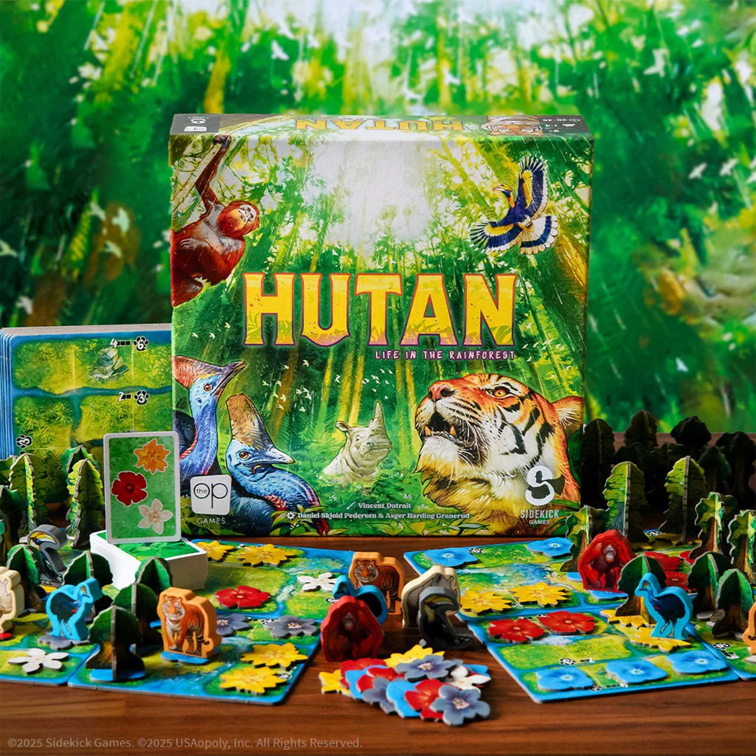 Eine Brettspielbox mit dem Titel 'Hutan' mit Regenwaldillustrationen. Spielsteine und Karten sind auf einem Holztisch angeordnet, die Tiere darstellen.