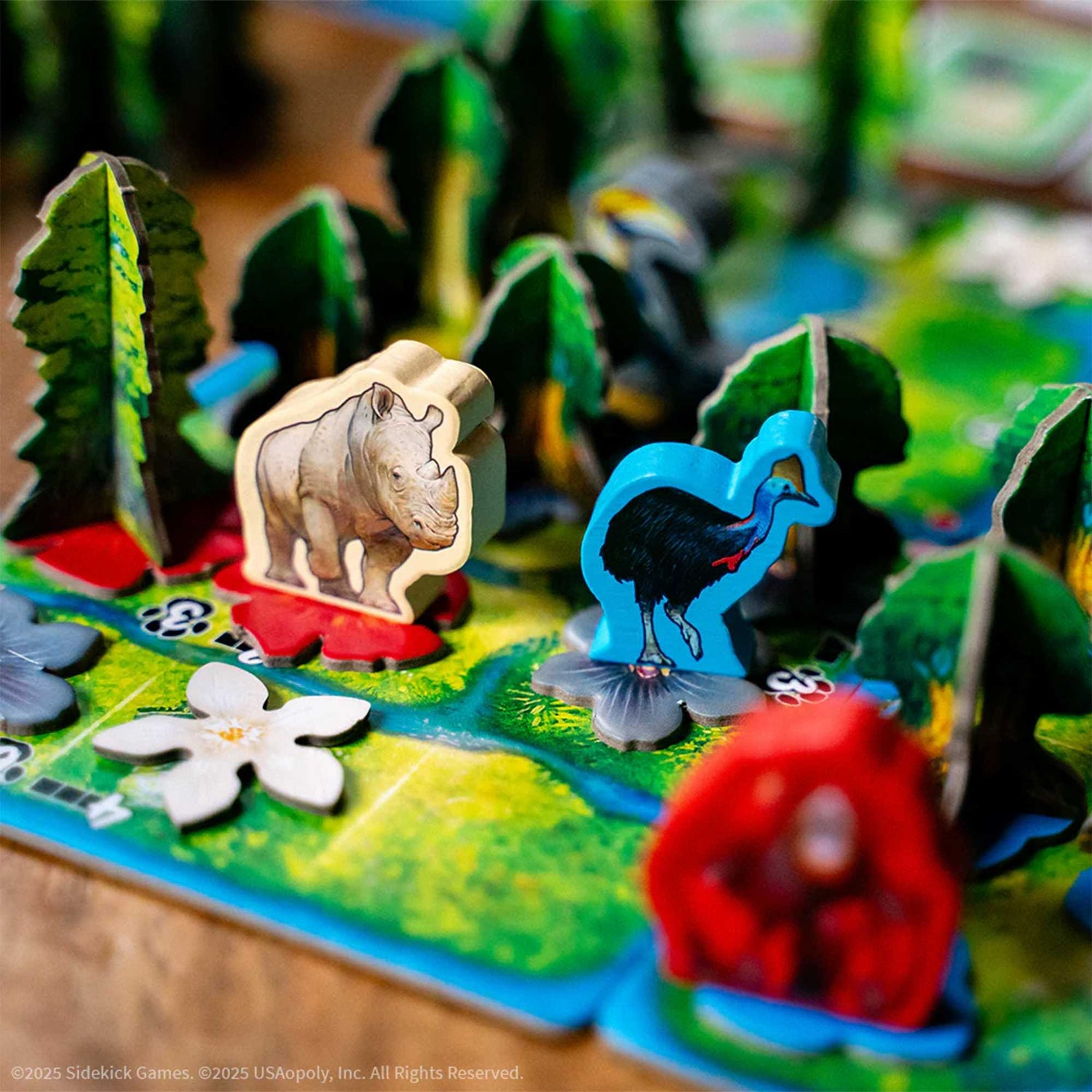 Ein Spielbrett mit Tierfiguren, Bäumen und Blumen. Ein Nashorn, ein blauer Vogel und ein roter Affe. Grün, Blau und Braun dominieren.
