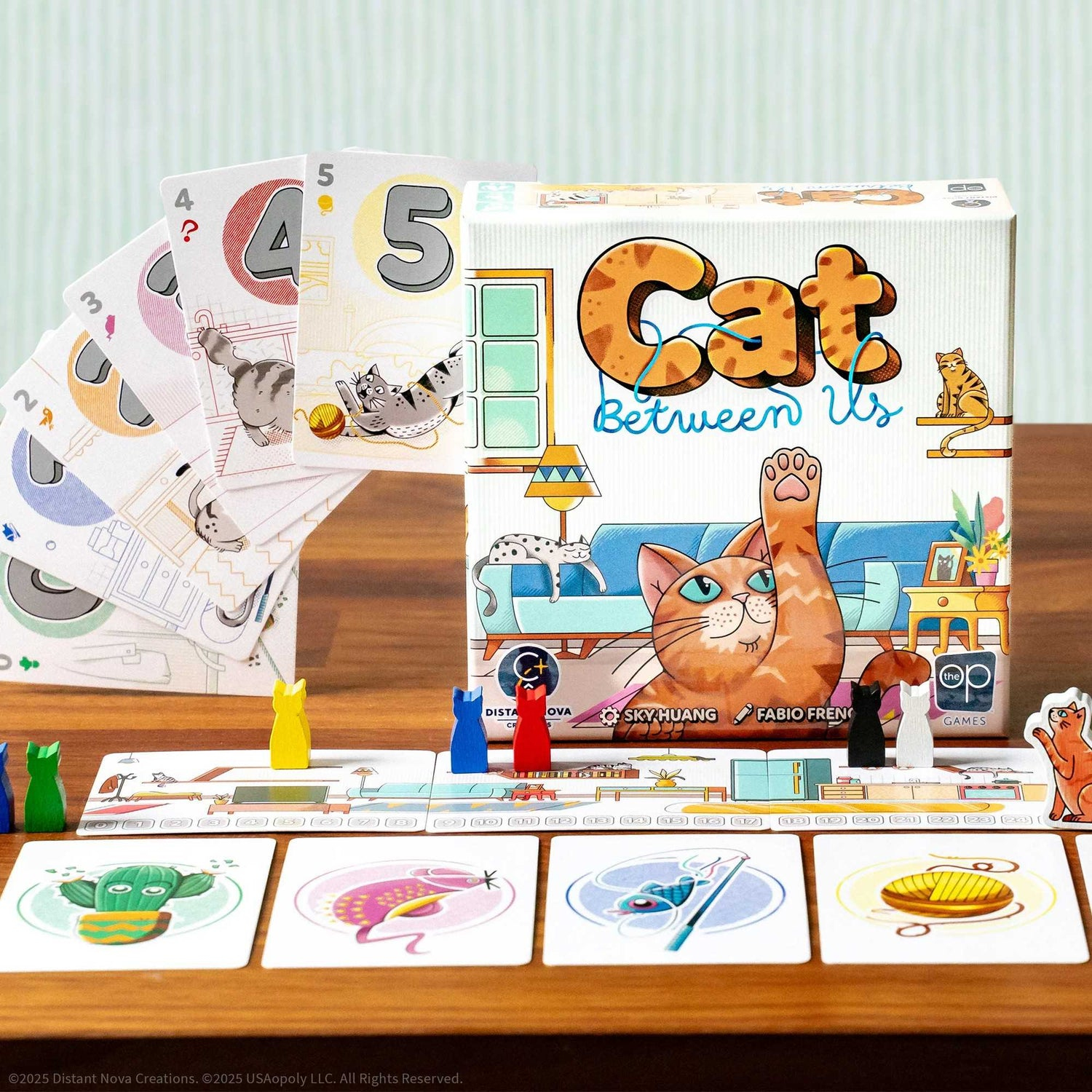 Ein Brettspiel namens "Cat Between Us" ist aufgebaut. Karten, Spielfiguren und Box-Art mit Katzenillustrationen sind sichtbar.