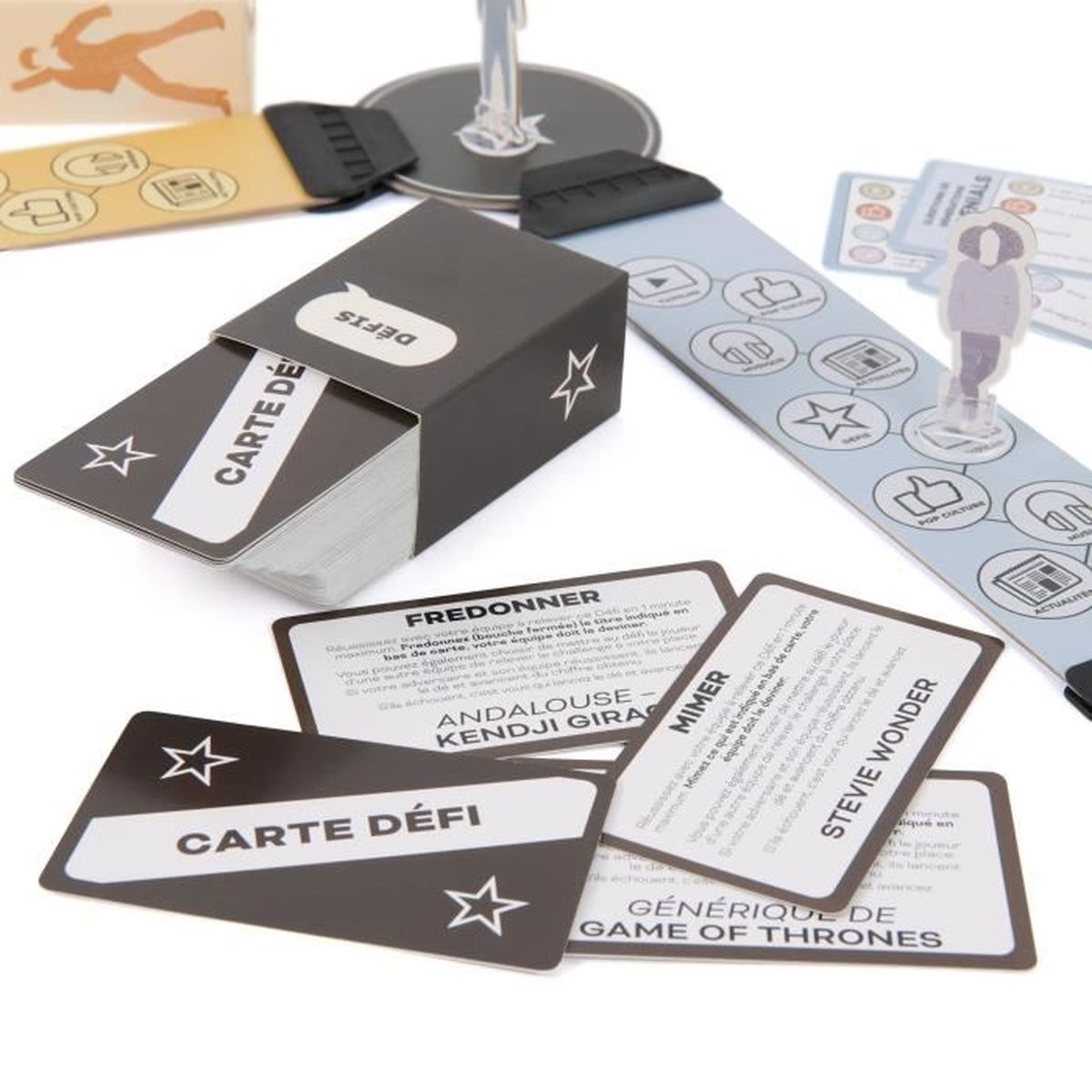 Een spel met kaarten, een doos en spelstukken. Op de kaarten staat 'Carte Defi' en 'Fredonner'. Een figuur staat op een spelstrook.