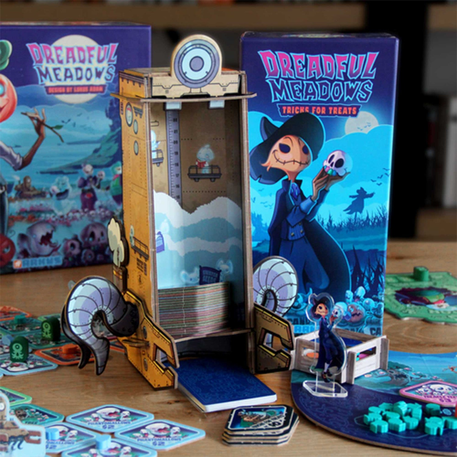 Ein Spielkarton 'Dreadful Meadows' mit einem Totenkopf, der einen Schädel hält. Spielsteine und eine Pappkonstruktion liegen auf einem Holztisch.
