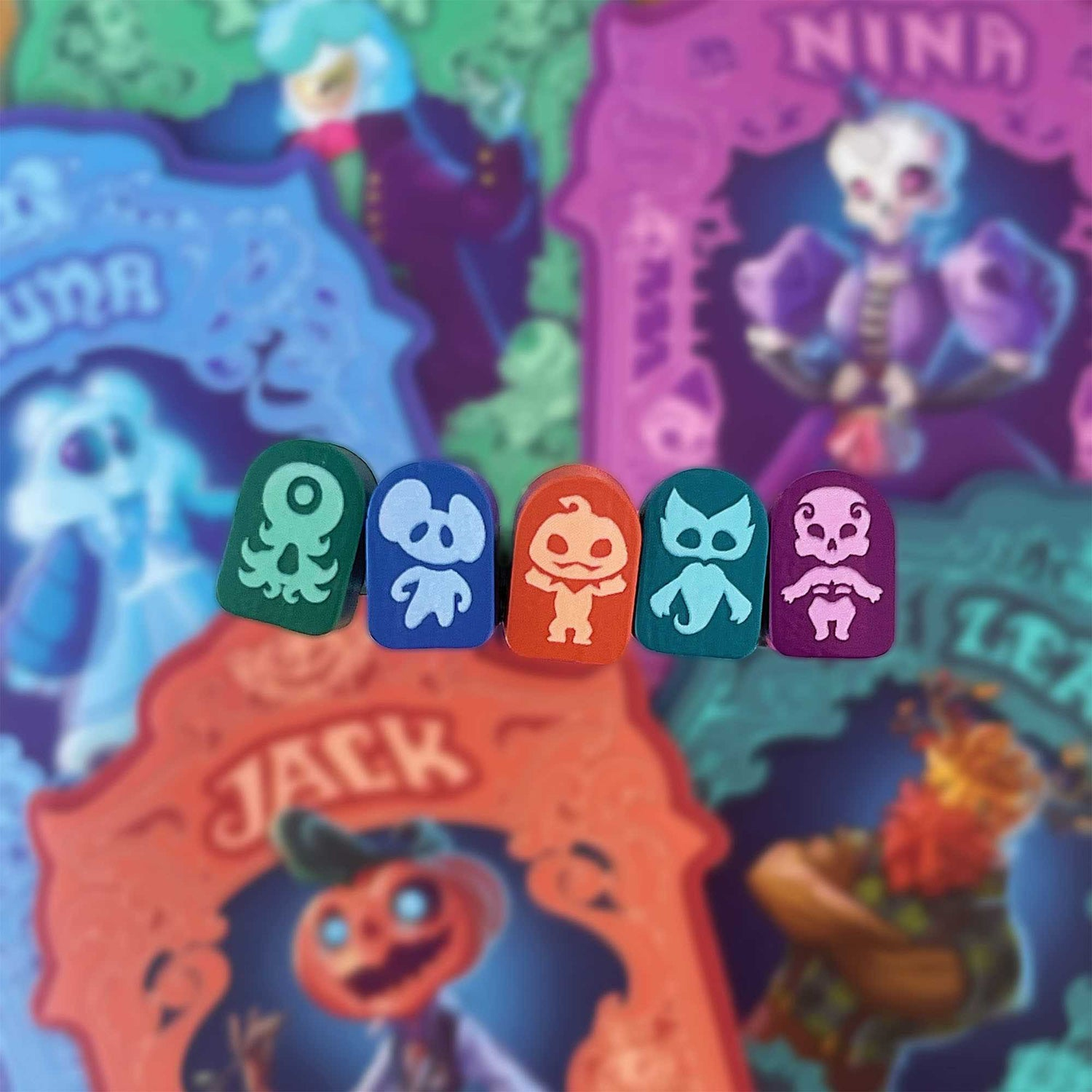 Fünf farbenfrohe Spielsteine zum Thema Halloween mit Charakterdesigns stehen im Fokus, mit verschwommenen Charakterkarten im Hintergrund.