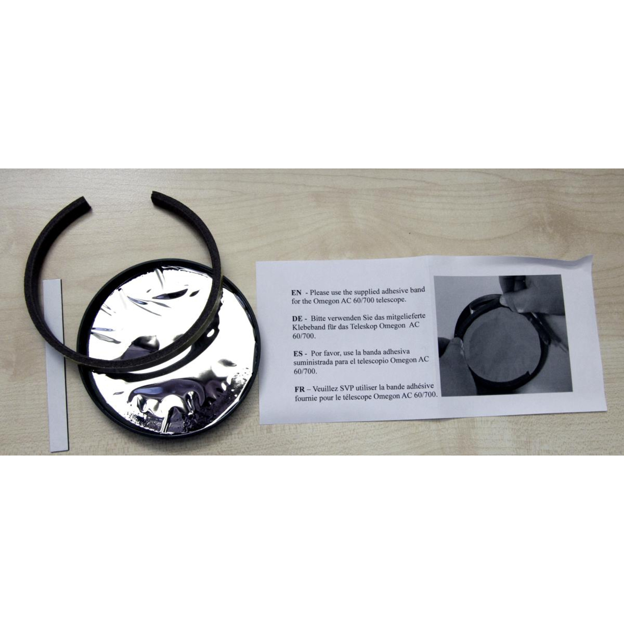 Das Bild zeigt Teleskopteile: zwei schwarze Ringe, eine reflektierende Scheibe und ein weißes Papier mit Anweisungen.