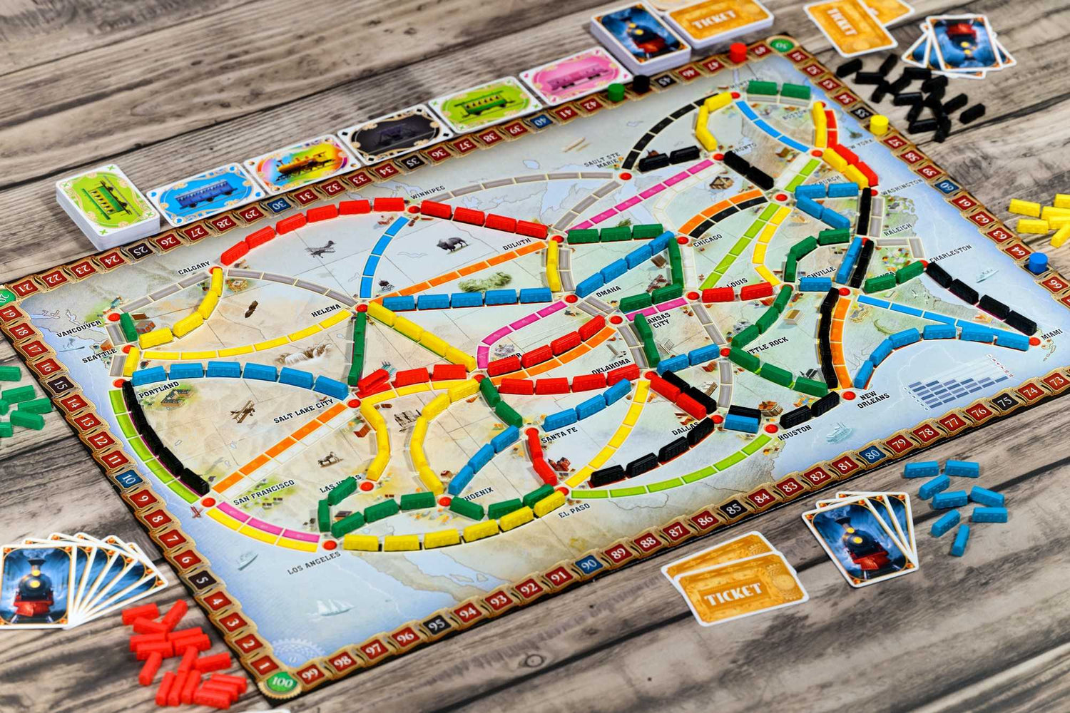 Brettspiel Ticket to Ride. Karte der USA mit farbigen Routen. Zugteile und Karten sind um das Brett verstreut.