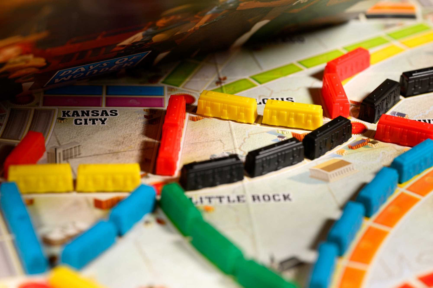 Nahaufnahme eines Brettspiels. Bunte Plastikzüge und Stadtmarkierungen sind auf einer Karte. Gelbe, rote, schwarze, blaue und grüne Teile sind sichtbar.