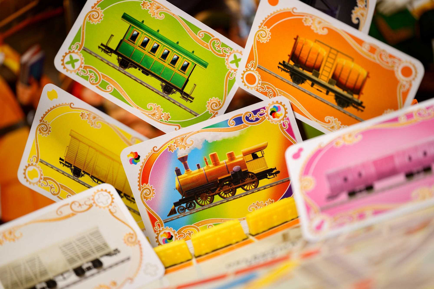Karten mit Zugillustrationen in verschiedenen Farben. Grüne, orange, gelbe und rosa Karten zeigen Zugwaggons.