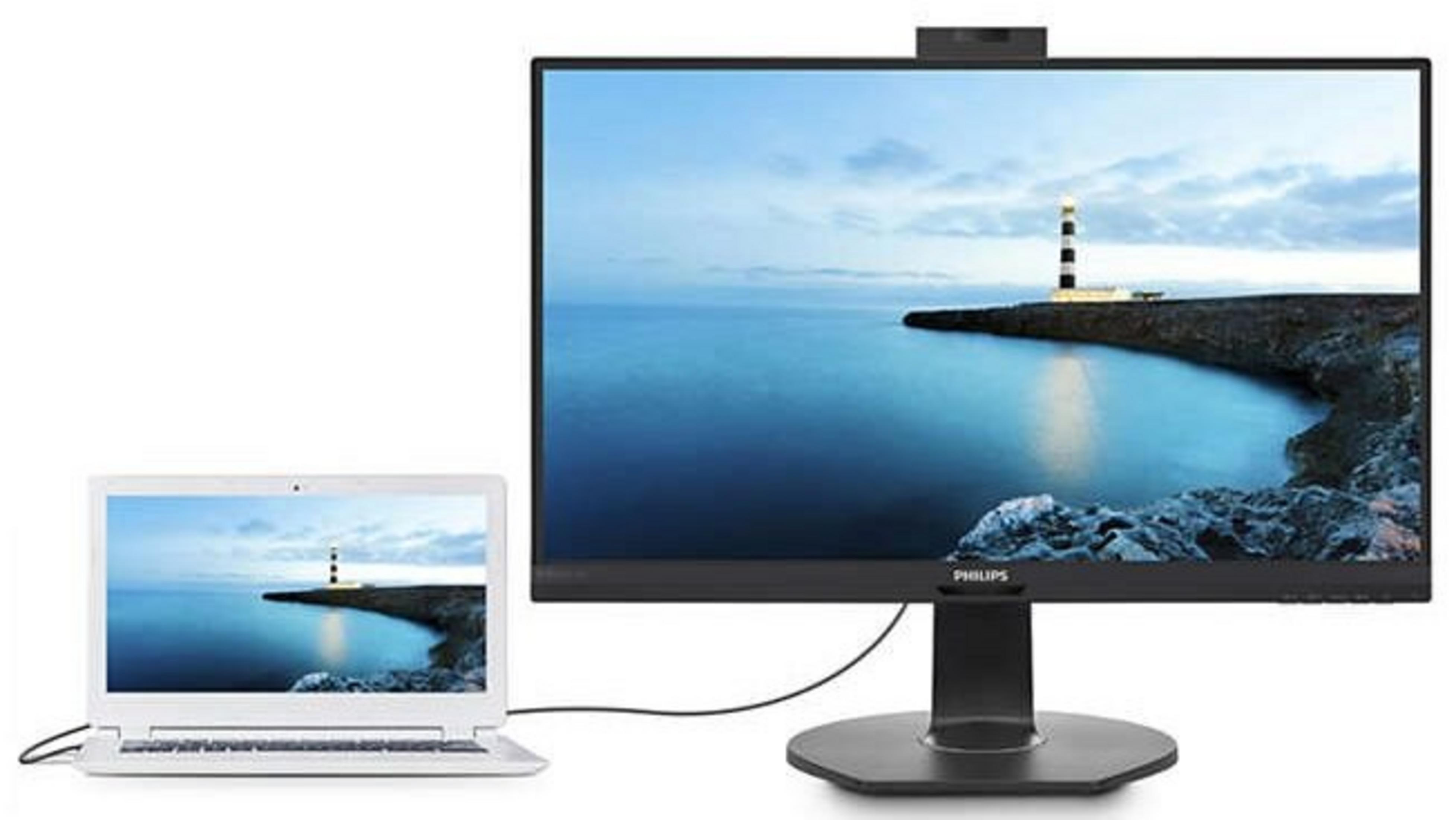 Una laptop y un monitor están conectados. Ambas pantallas muestran una escena de faro sobre el agua. El monitor tiene una cámara web.