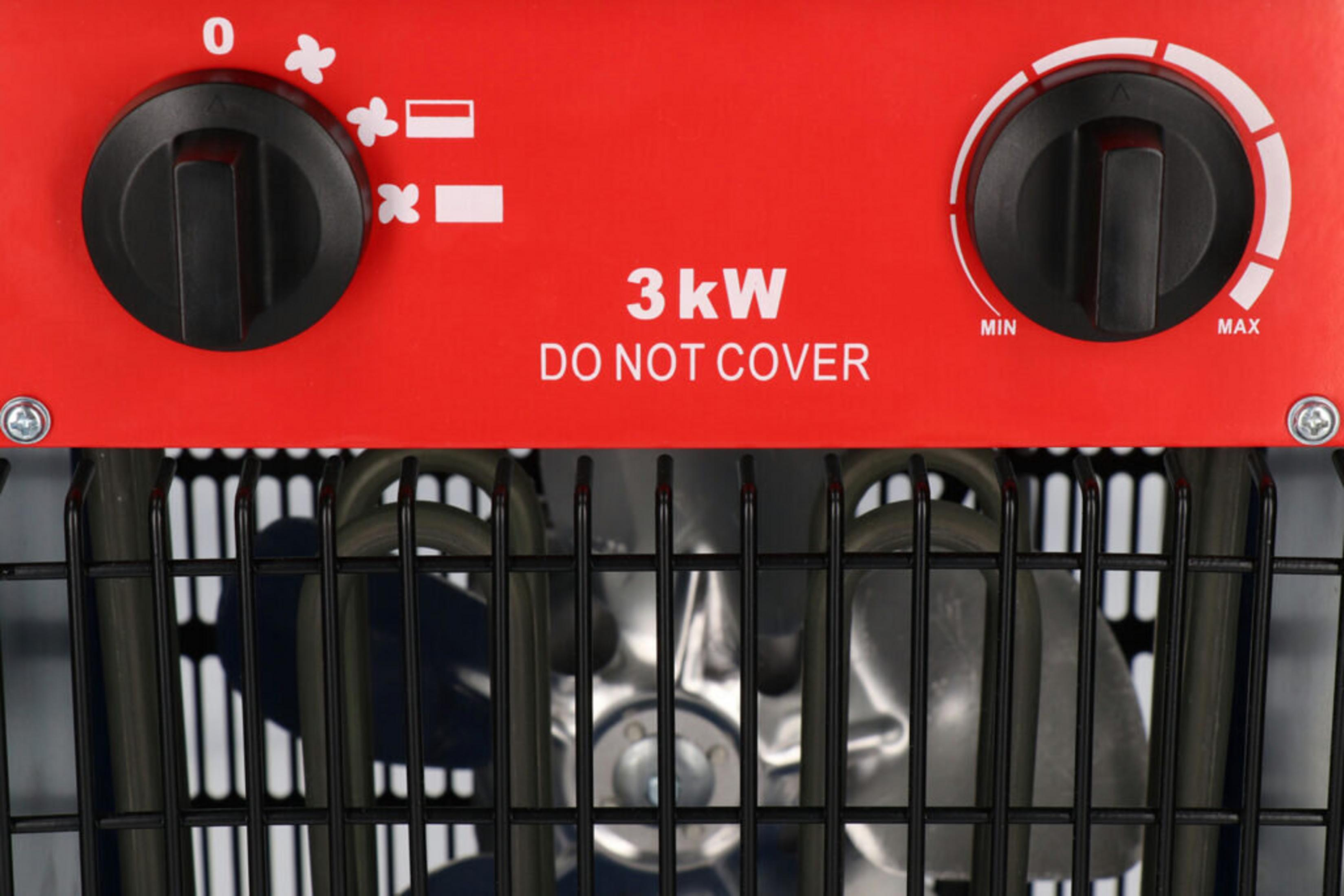 Roter Heizlüfter mit schwarzen Bedienelementen und einem Drahtgitter. Text: '3kW NICHT ABDECKEN'.