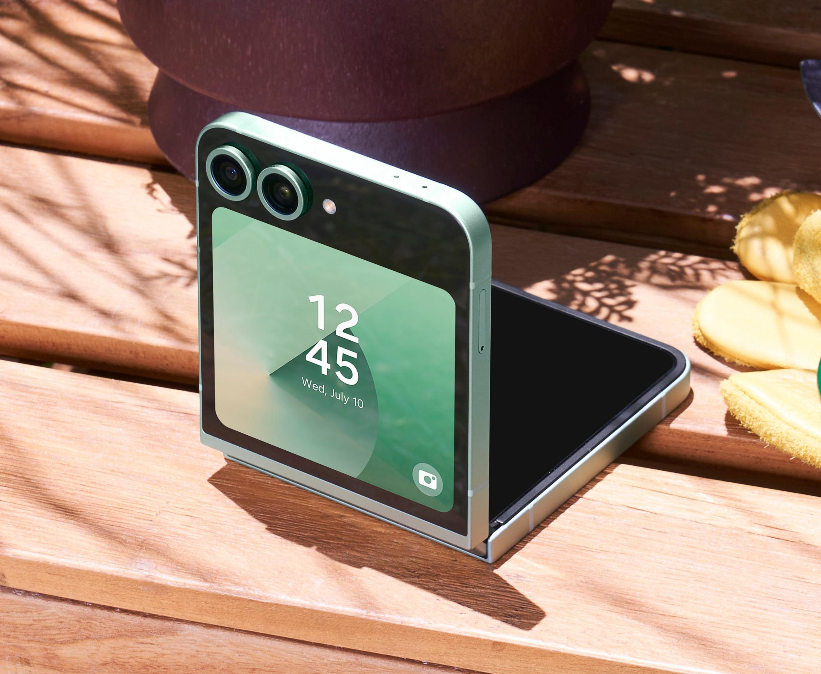 Otwarty miętowy składany telefon pokazuje godzinę. Leży na drewnianej powierzchni.