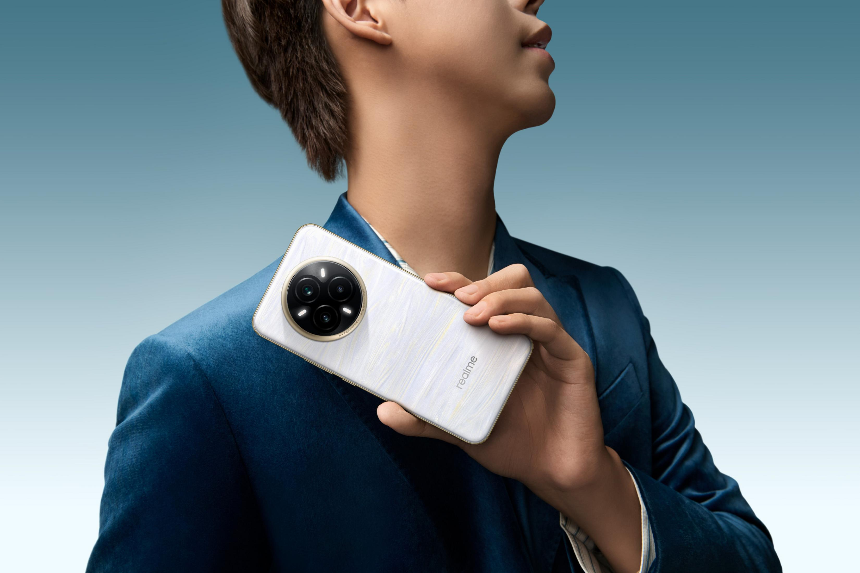 Osoba trzyma biały telefon z okrągłym modułem aparatu. Ma na sobie niebieską marynarkę na niebieskim tle.