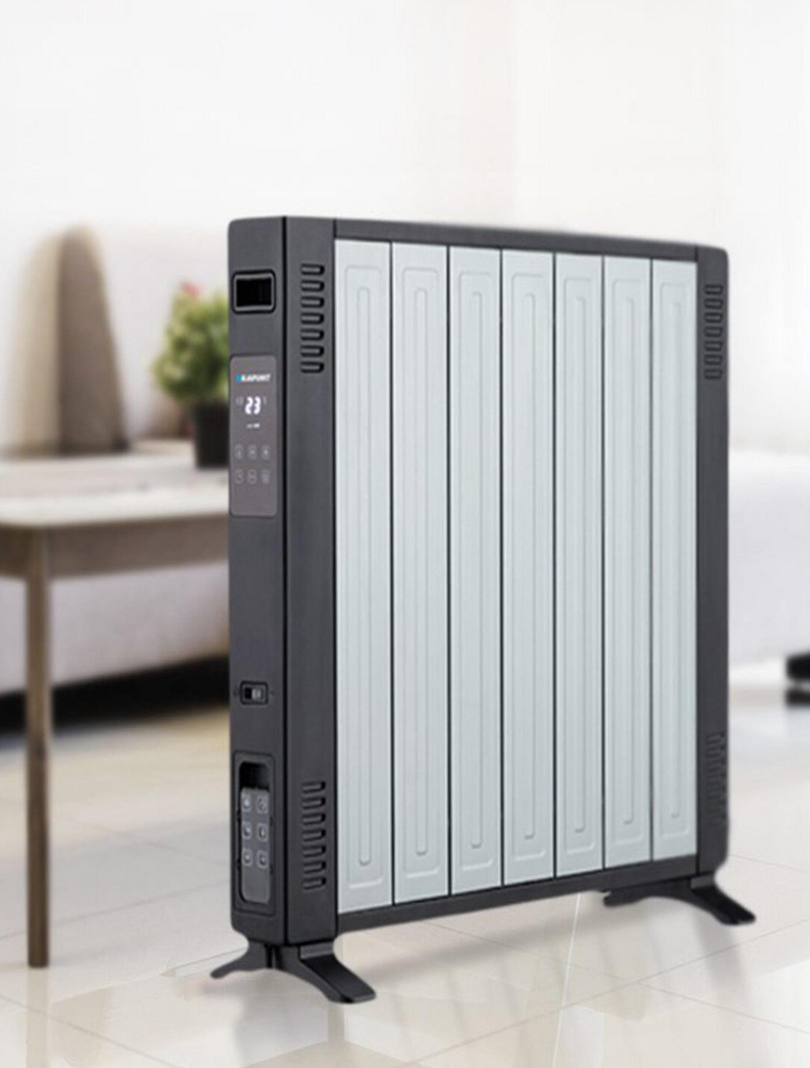 Un moderno calefactor eléctrico negro y plateado está en una habitación. Tiene una pantalla digital y un panel de control.