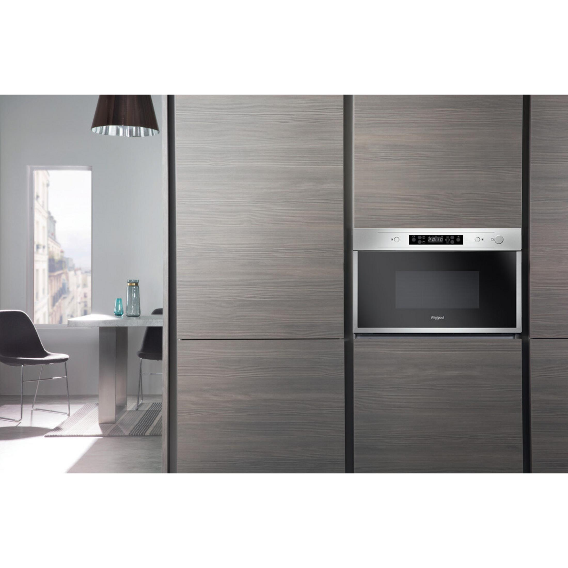 Interni cucina con forno a microonde integrato in mobili in legno. Tavolo e sedie parzialmente visibili.