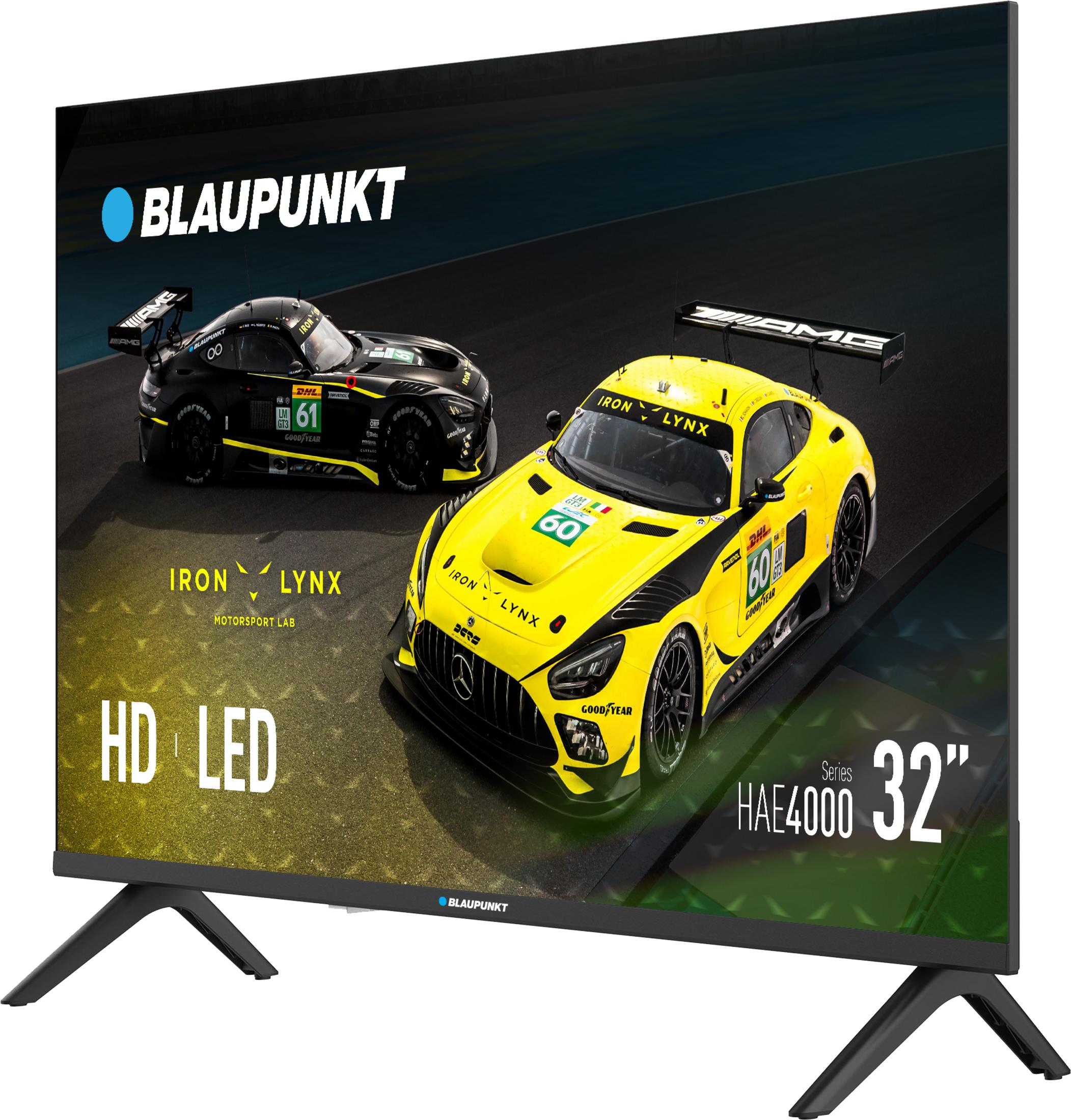 Telewizor Blaupunkt wyświetla dwa samochody wyścigowe, jeden żółty, drugi czarny, na torze. Tekst zawiera 'Iron Lynx' i 'HD LED'.
