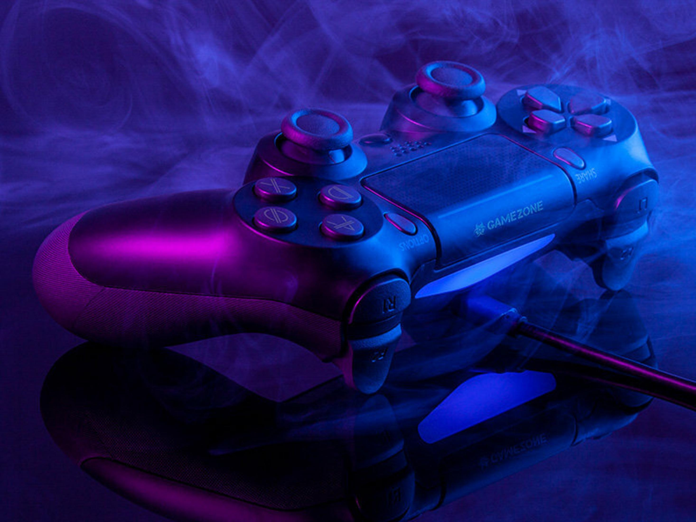 Un controller di gioco nero è illuminato da luci viola e blu, con un riflesso sottostante. Il fumo riempie lo sfondo.