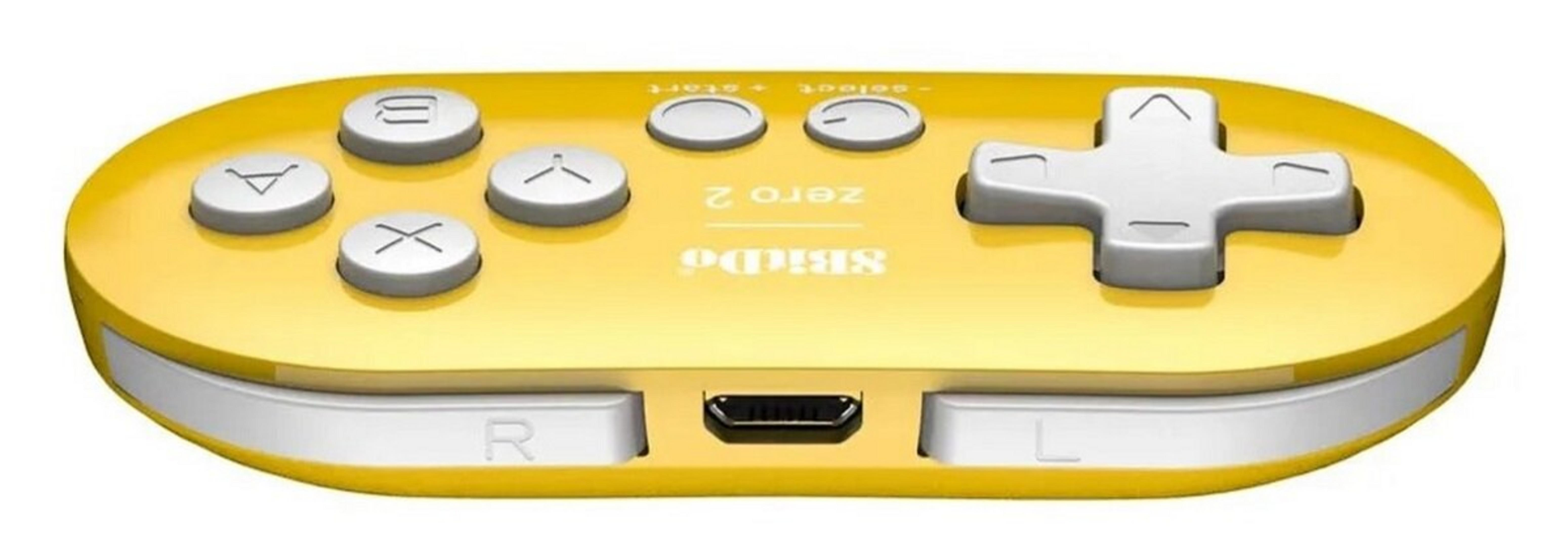 Żółty kontroler do gier z białymi przyciskami, krzyżakiem i portem USB. Marka to 8BitDo Zero 2.
