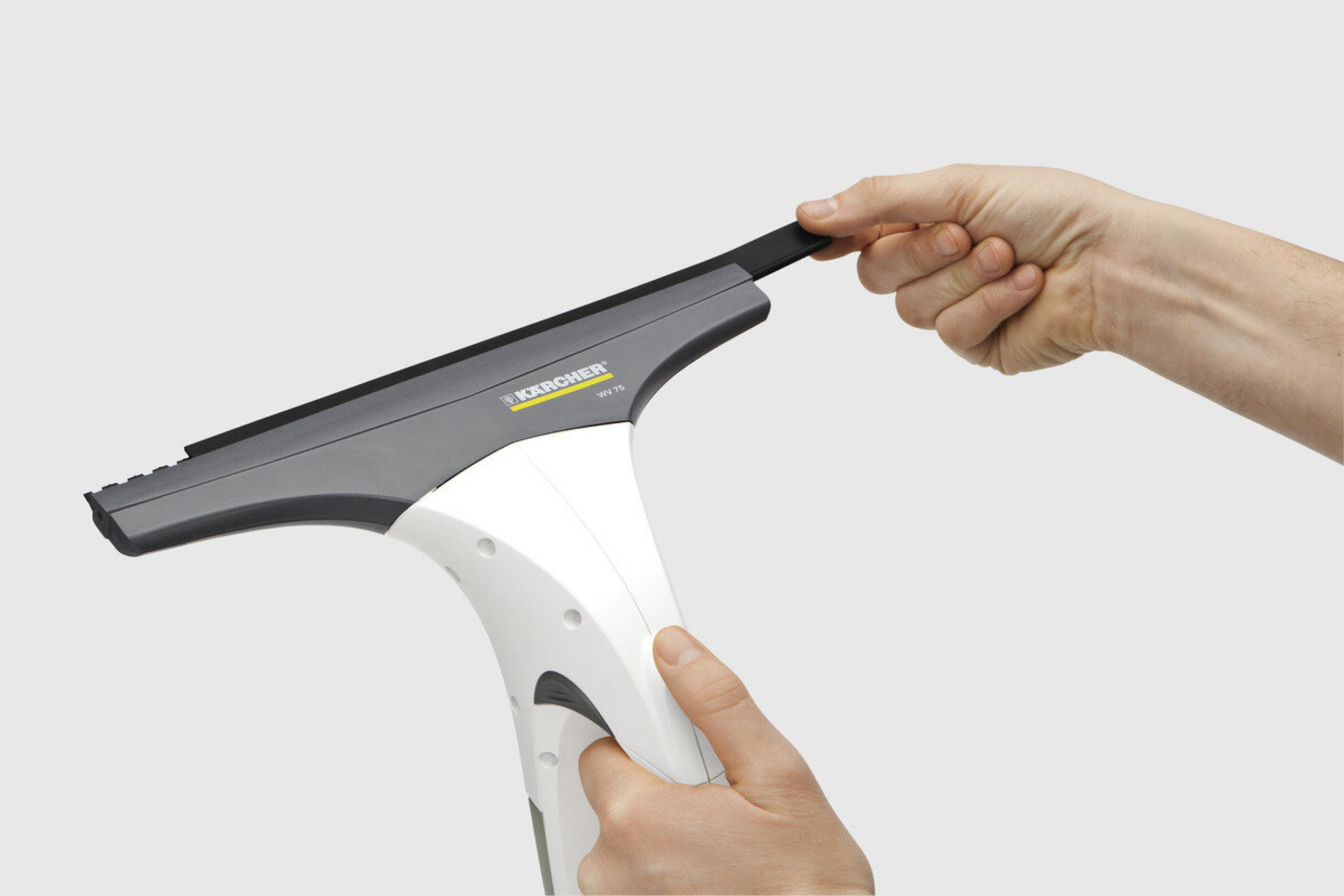 Ręka trzyma myjkę do okien Kärcher. Urządzenie ma biały uchwyt i szarą głowicę. Tło jest białe.