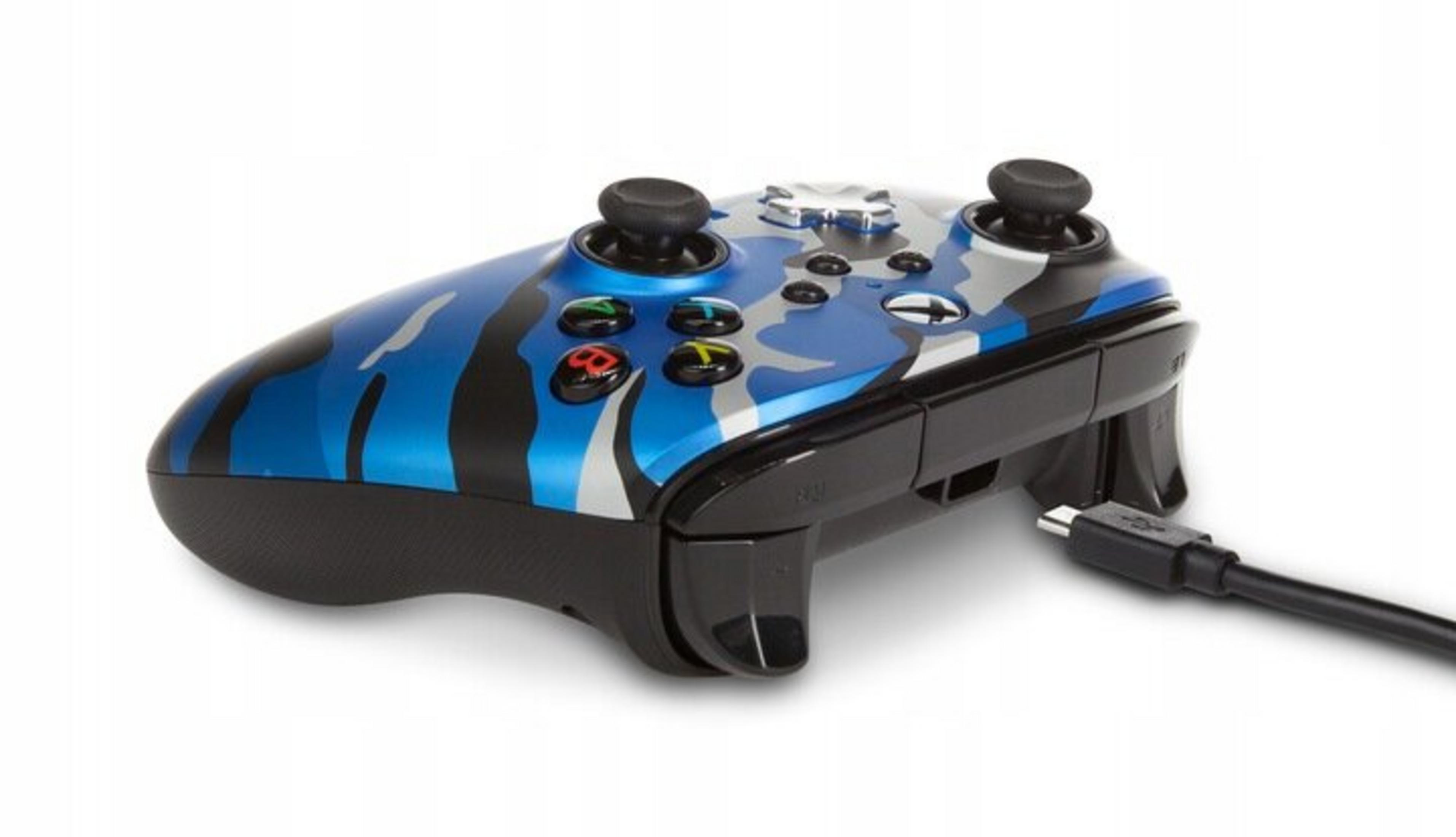 Un controller Xbox mimetico blu, nero e argento con cavo di ricarica su sfondo bianco.