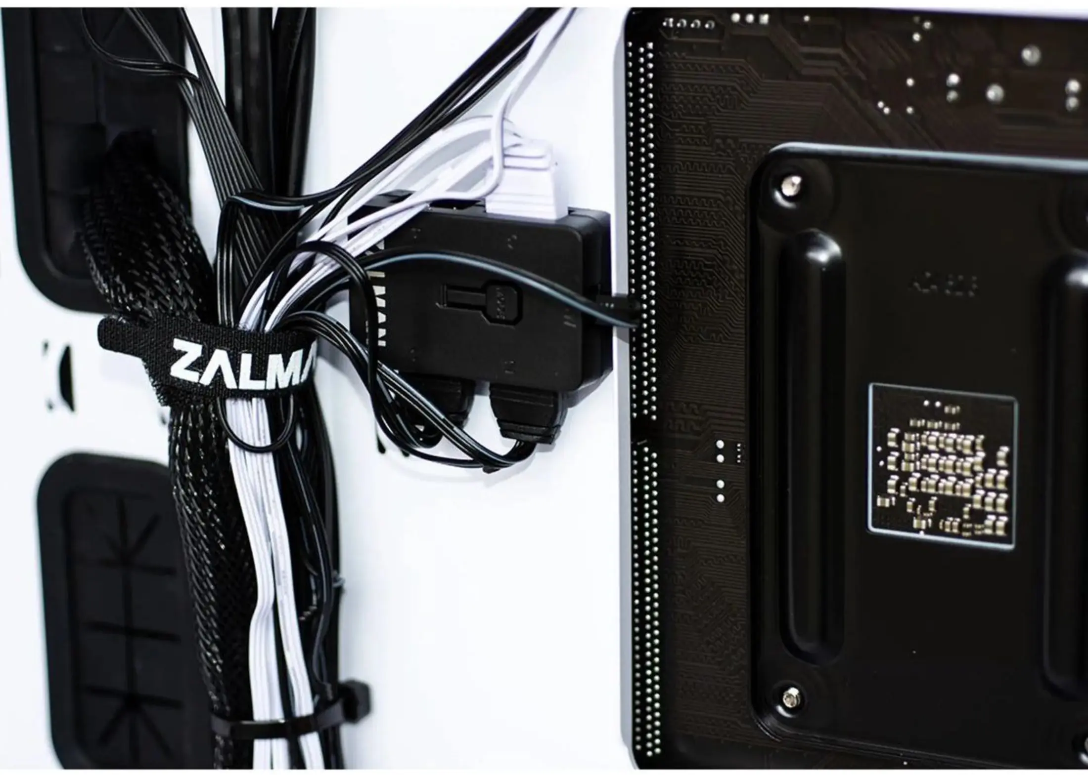 PC-componenten: zwarte en witte kabels, een zwarte kabelorganizer met 'ZALMAN'-logo, een zwarte connector en een zwarte PCB.