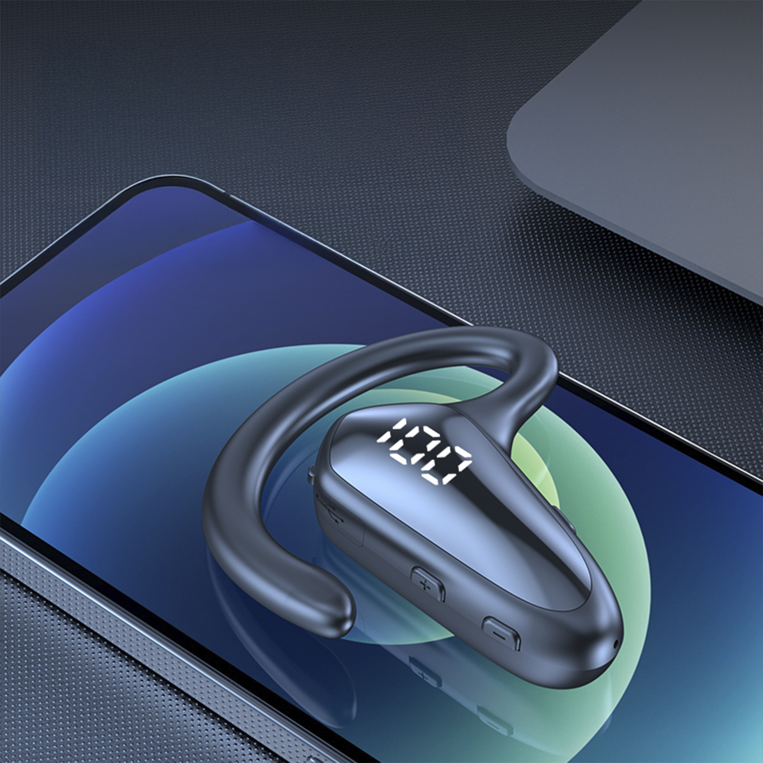 Un auricolare Bluetooth grigio scuro con display digitale che mostra '100' è appoggiato su uno smartphone. Lo schermo mostra una sfumatura blu.